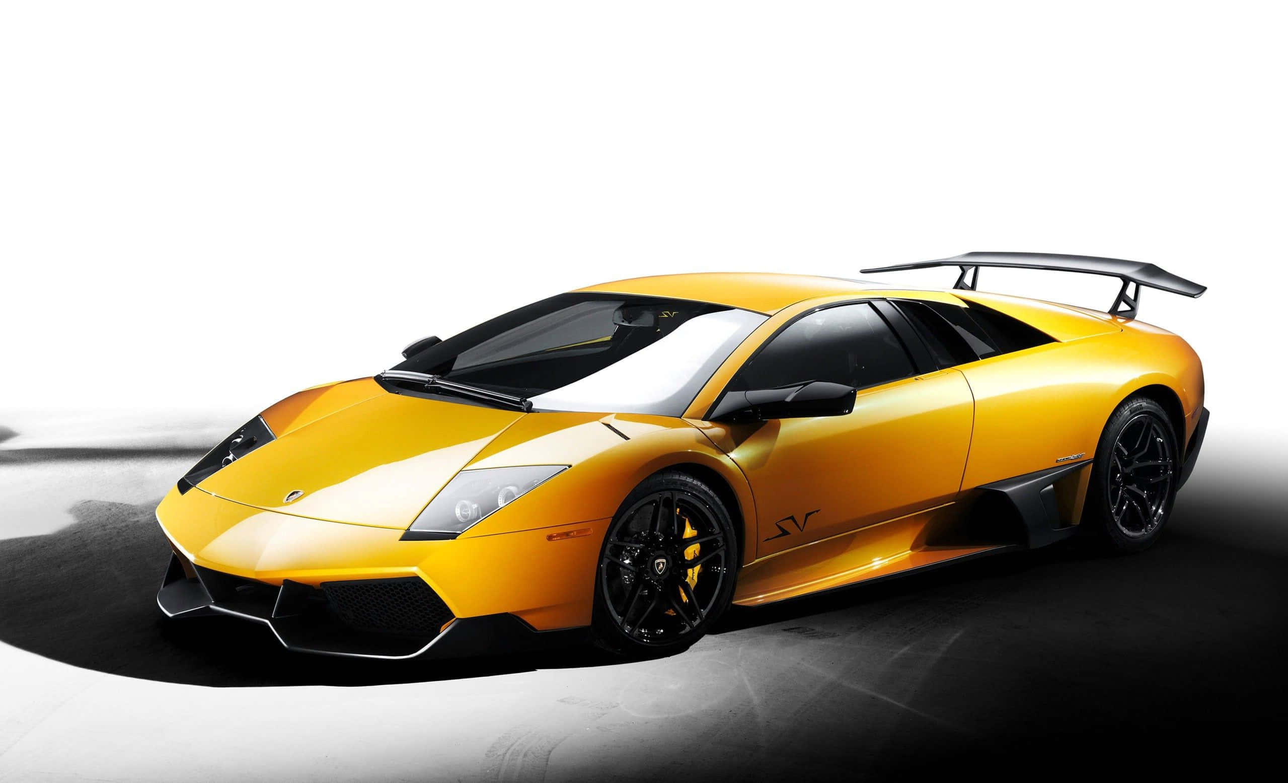 Lamborghini Murciélago 桌布 壁紙 — 一輛鮮黃色的林寶堅尼跑車，帶有黑色飾件和後擾流板，在黑白攝影棚背景下戲劇性地擺放。