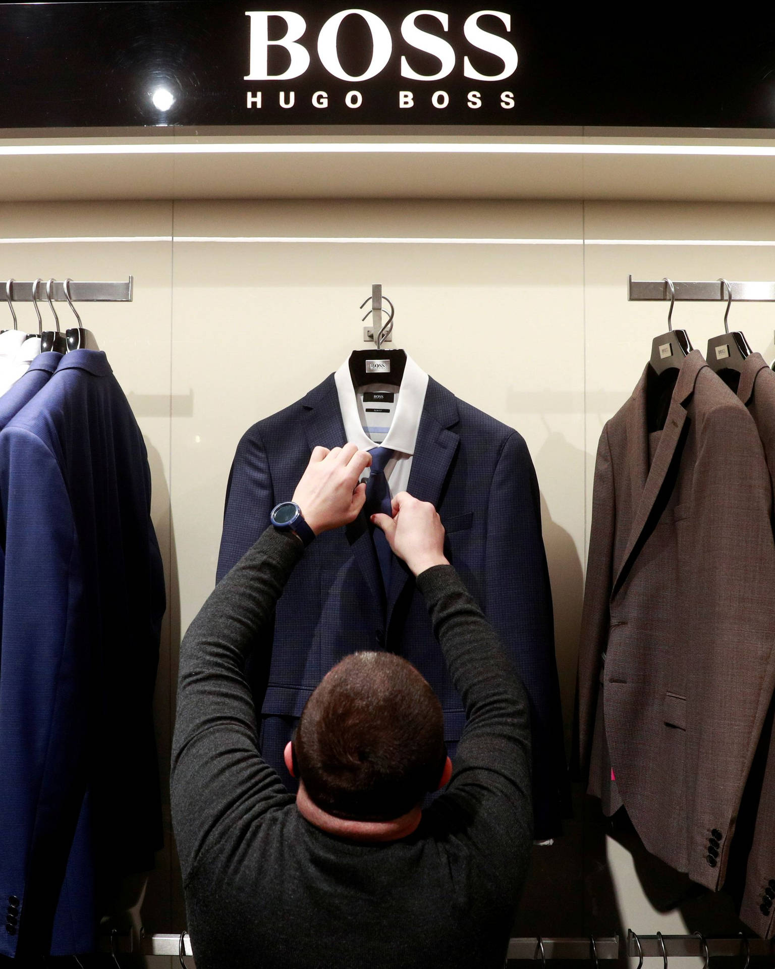 在零售店中調整 Hugo Boss 西裝人體模型領帶的人。