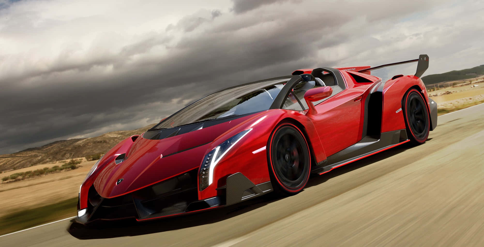 Lamborghini Veneno 桌布 壁紙 — 一輛鮮紅色的林寶堅尼 Veneno 在戲劇性的多雲天空下，沿沙漠公路飛馳。
