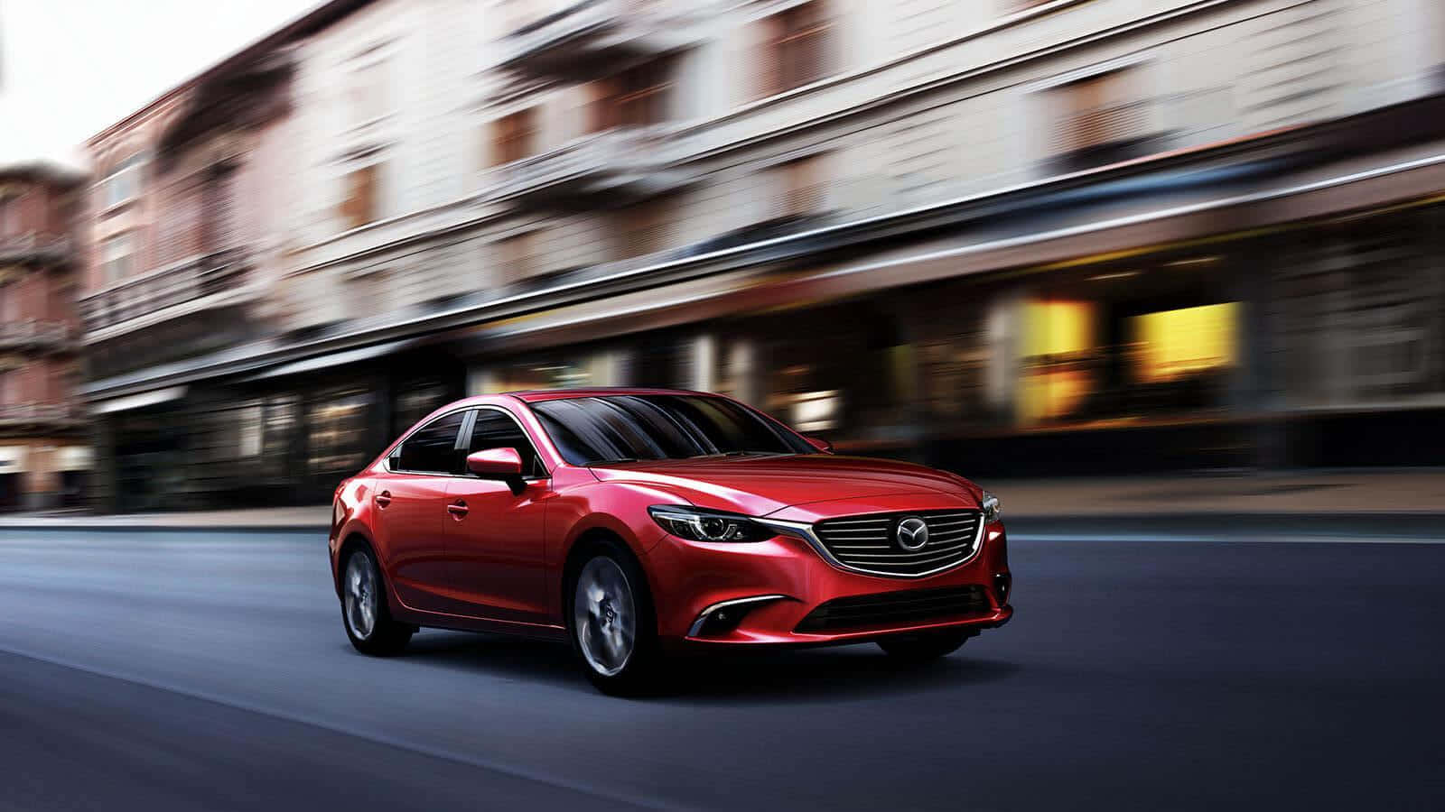 Mazda 6 桌布 壁紙 — 一輛鮮紅色的萬事得房車在城市的街道上飛馳，模糊的建築物在運動中急速掠過。