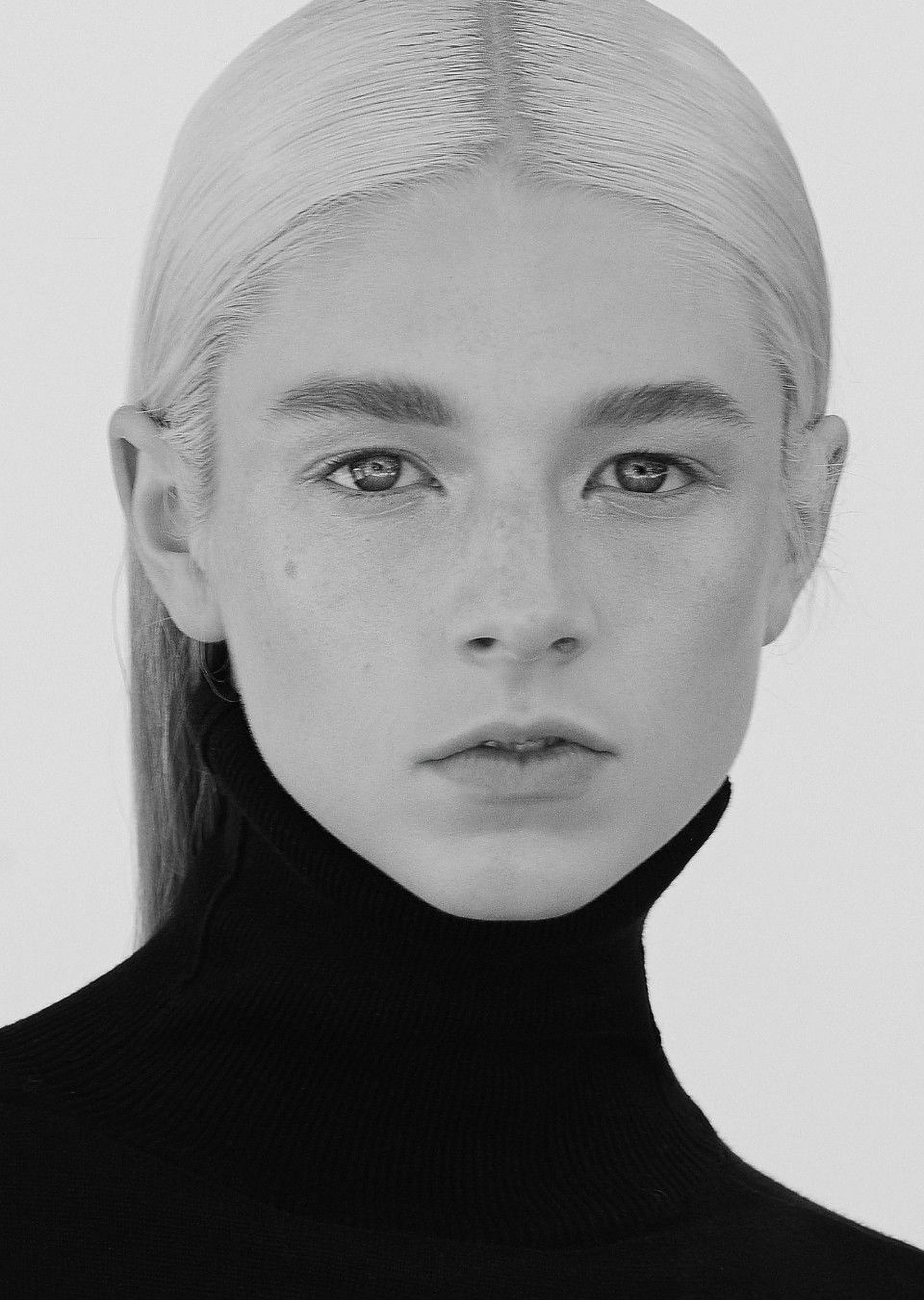 Hunter Schafer 近距離肖像 壁紙 — 一個引人注目的黑白肖像，一位年輕女性擁有鉑金色頭髮和雀斑，穿著高領 turtleneck。