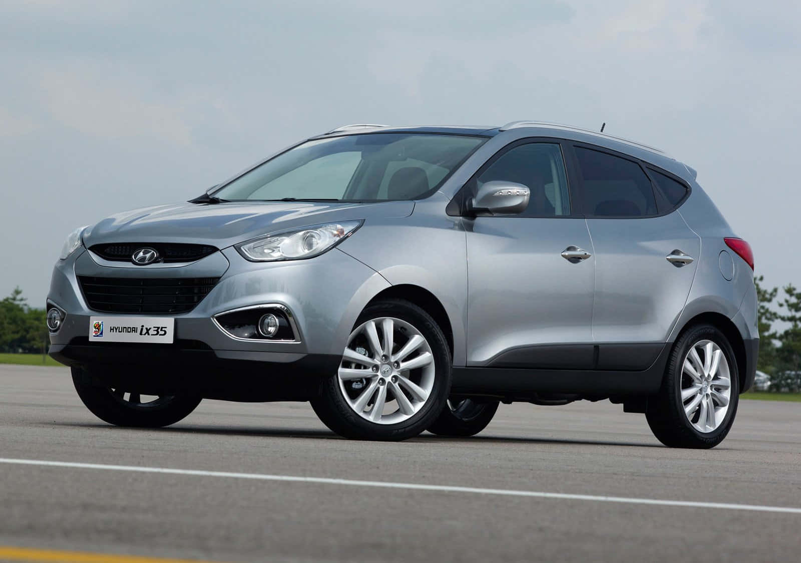 銀色Hyundai ix35 SUV停泊在瀝青路面上，後面有樹木。