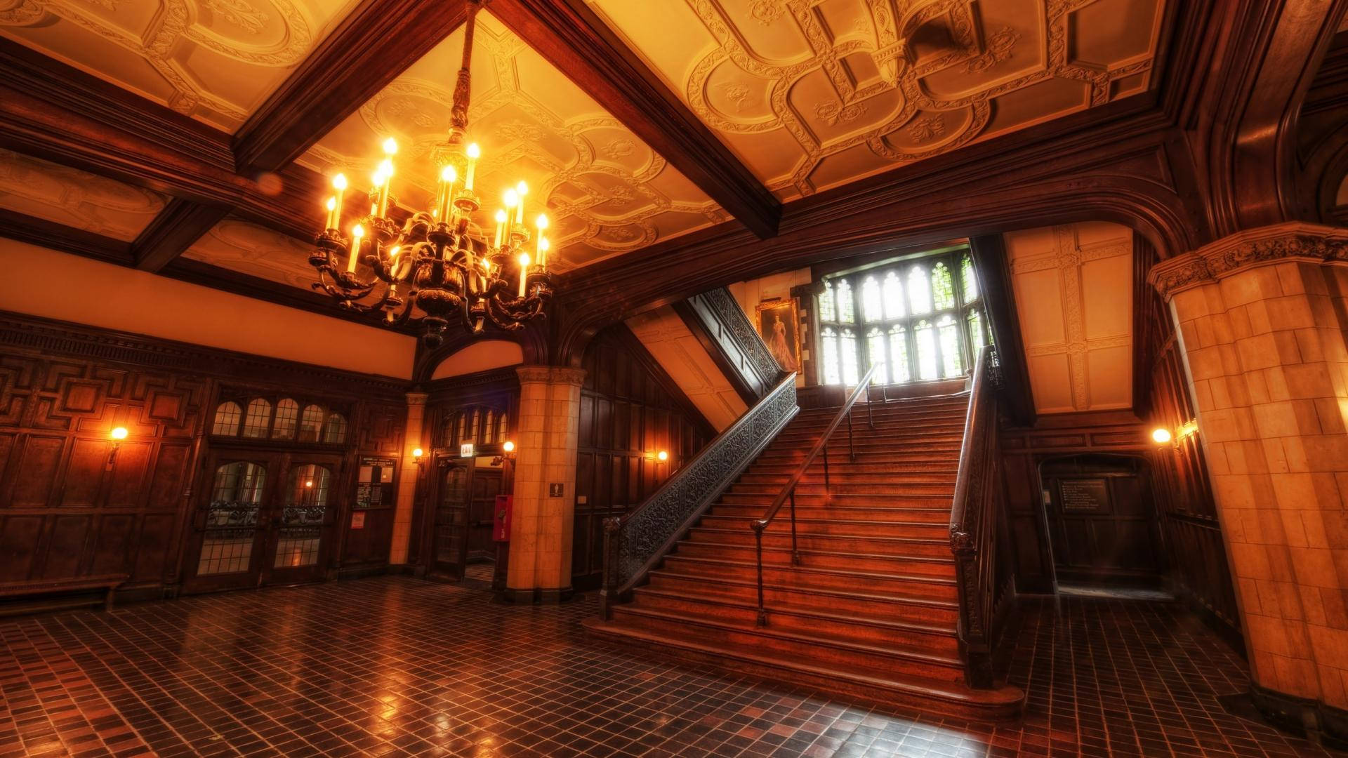 Ida Noyes Hall 內部設計 壁紙 — 華麗的歷史大廳中，由吊燈照亮的宏偉木樓梯，配以瓷磚地板和精緻天花板。