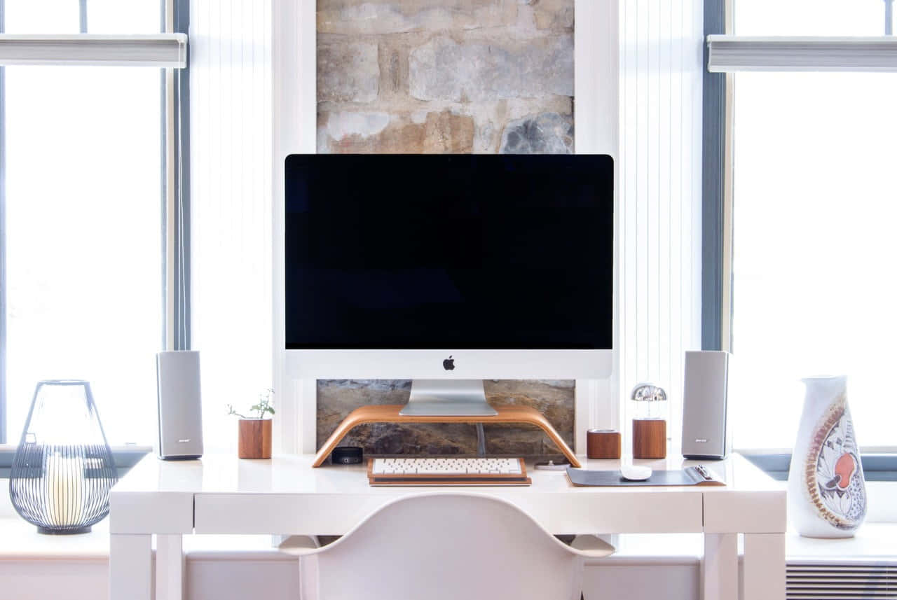 簡約家居辦公室，配備 iMac、揚聲器和裝飾，在明亮的窗戶下。