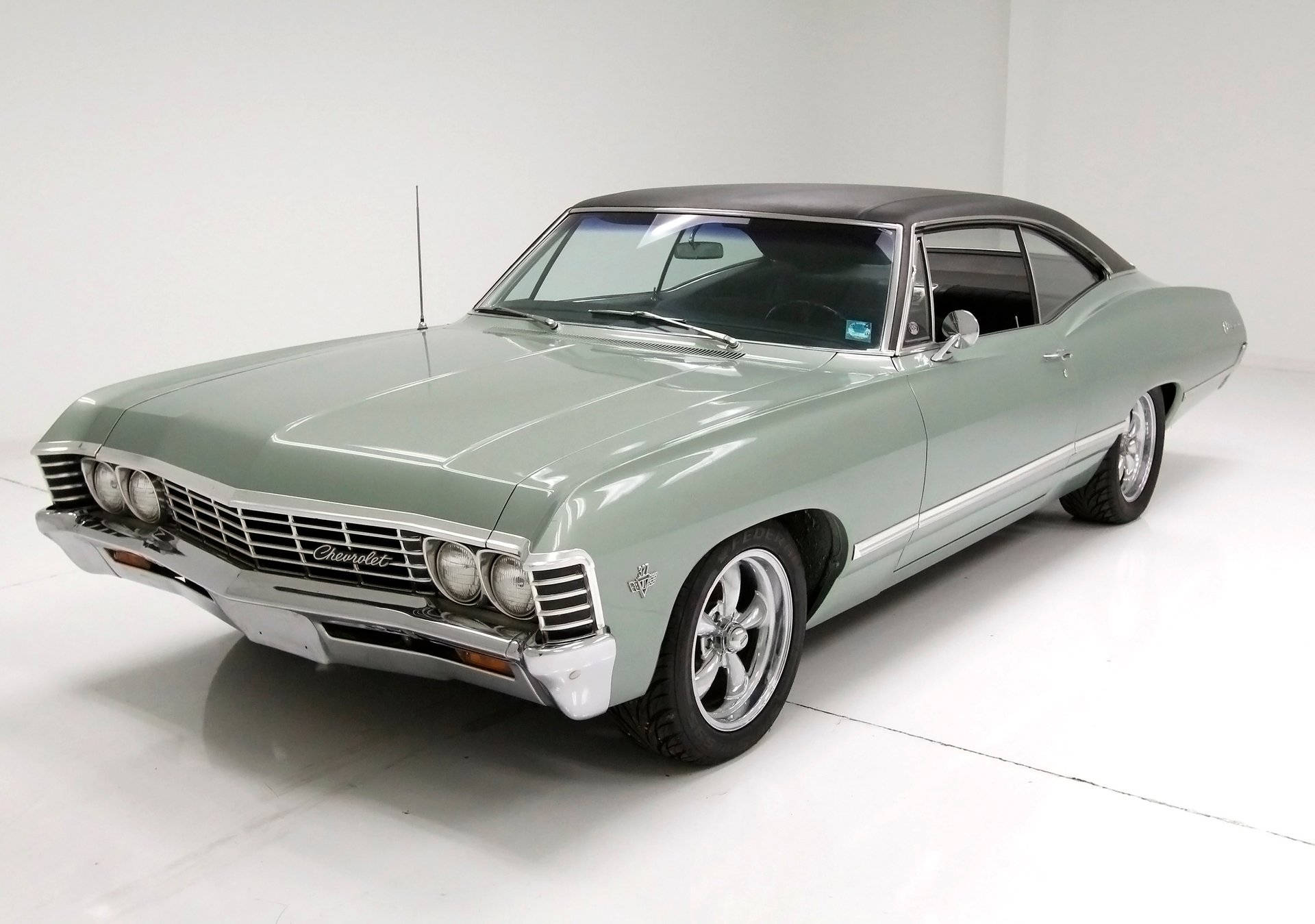 草綠色雪佛蘭Impala 1967 壁紙 — 一輛時尚的薄荷綠經典雪佛蘭，黑色車頂和鍍鉻細節在明亮的攝影棚燈光下閃閃發光。