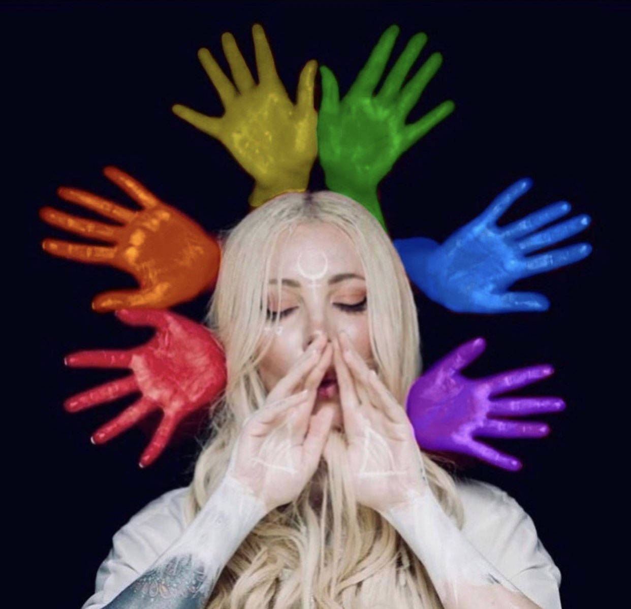 In This Moment 獲 Pride Month 獻禮 壁紙 — 一個閉上眼睛、雙手掩嘴的女人，被六隻發光的彩虹色手環繞，背景為黑色。