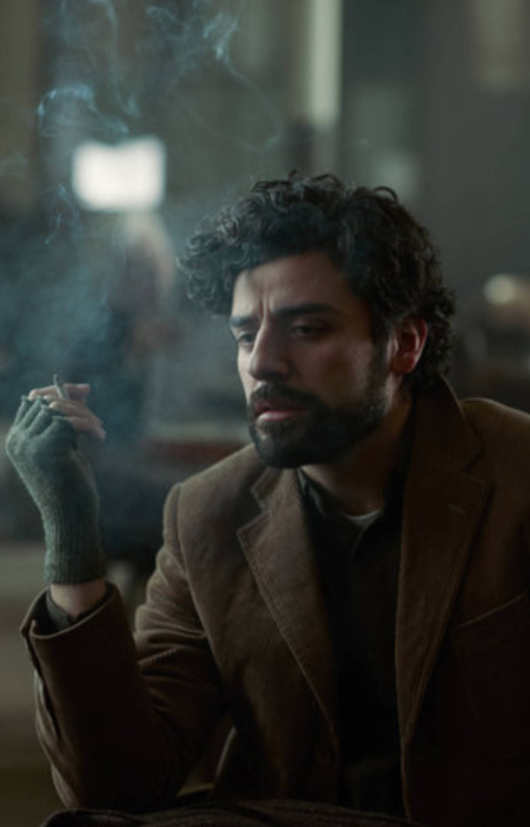 《Inside Llewyn Davis》抽煙場景 壁紙 — 一個深色捲髮和鬍鬚的男人在昏暗的房間裏抽煙，煙霧向上繚繞。