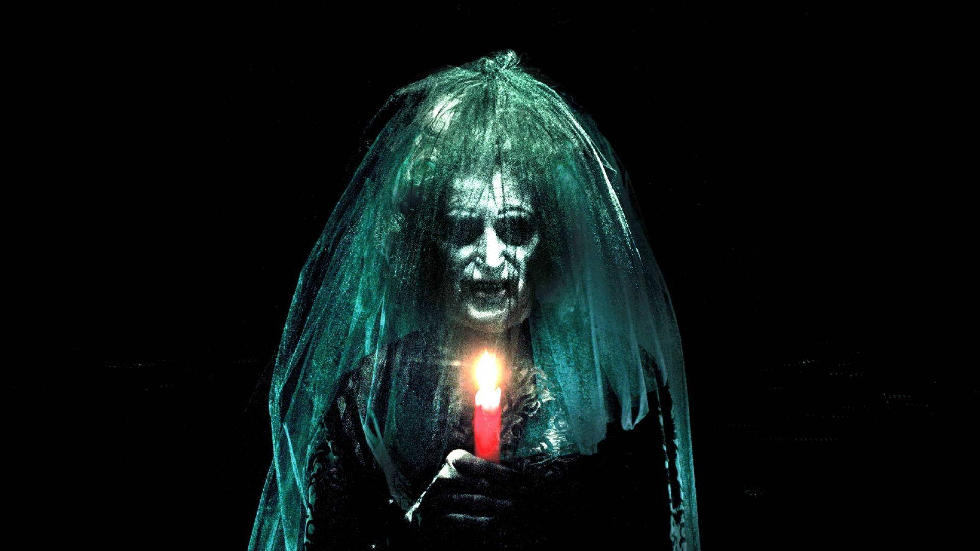 黑紗新娘：Insidious 壁紙 — 一個幽靈般的新娘，披著破爛的面紗，在漆黑的背景下手持一支閃爍的紅色蠟燭。