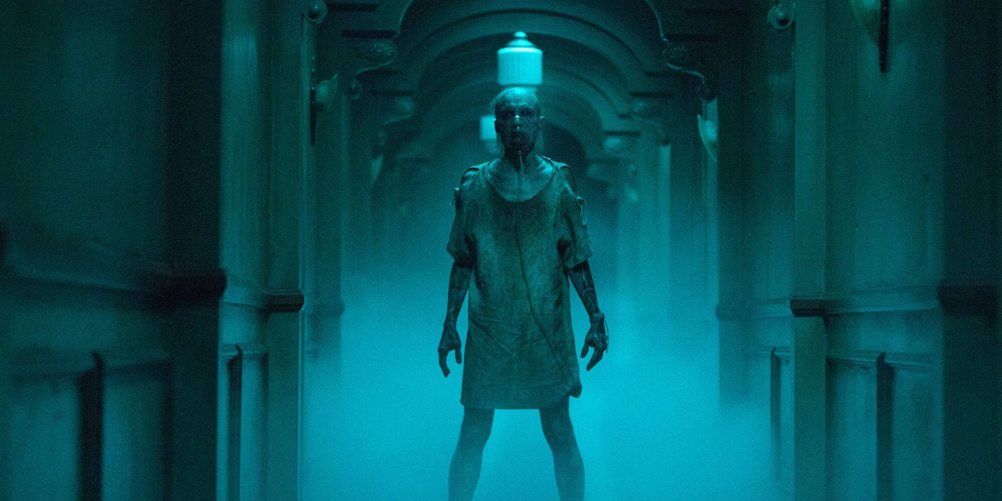 無法呼吸的男人：Insidious 第三章 壁紙 — 一個蒼白的人形身影站在霧氣瀰漫、青綠色照明的走廊中，有華麗的拱門和上方懸掛的燈。