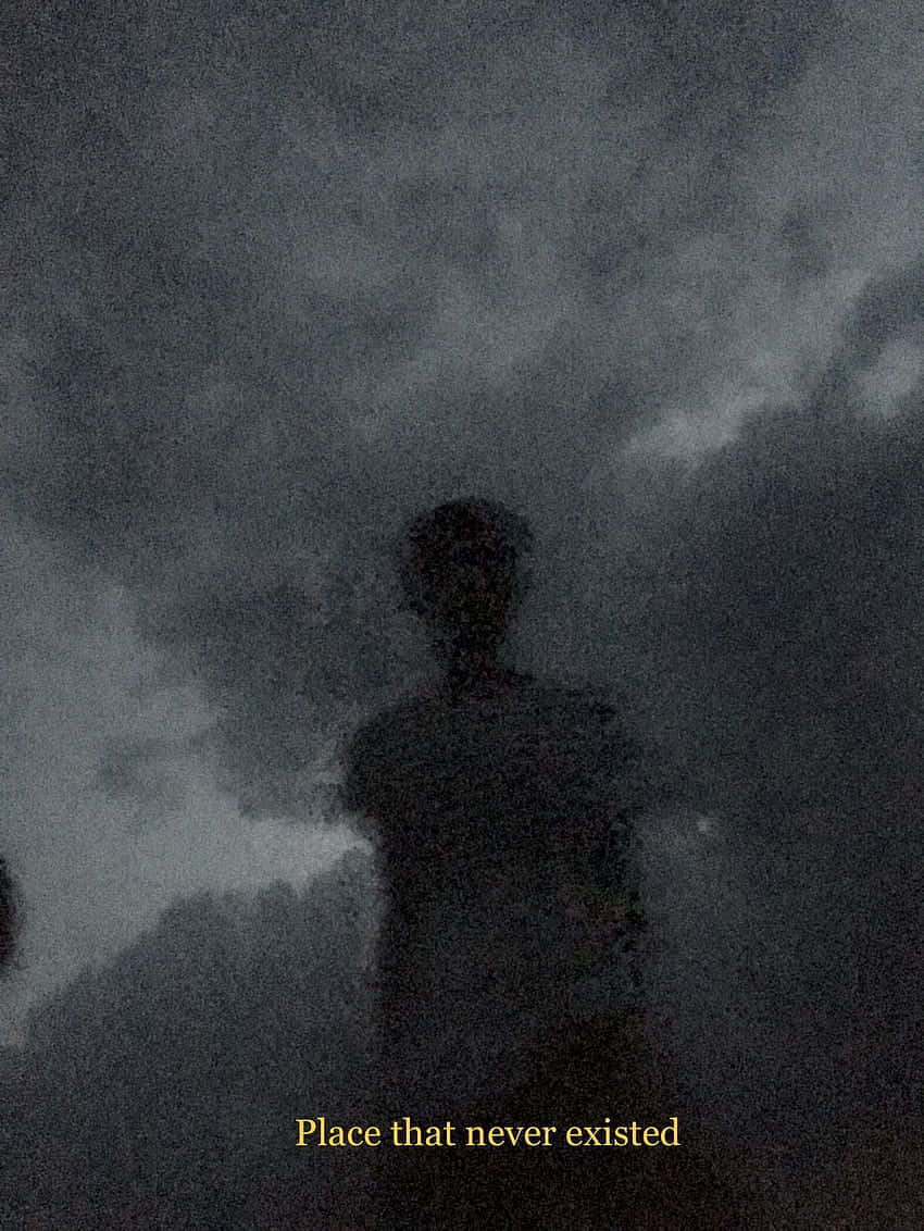 模糊剪影 Instagram 大頭貼 壁紙 — 一個幽靈般的人形剪影，站在帶有微弱雲層和顆粒感電影效果的紋理深灰色天空前。