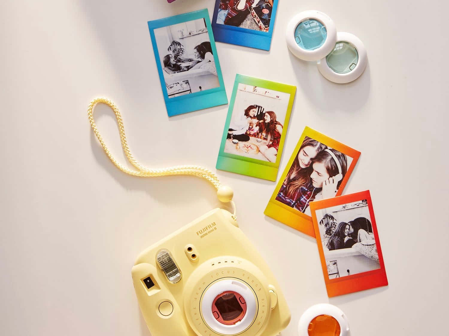 黃色即影即有相機，配色彩繽紛嘅寶麗來相片同鏡頭配件，喺白色表面上。