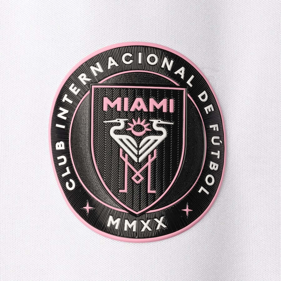Inter Miami FC 官方隊徽標誌 壁紙 — 白色布料背景上，黑色和粉紅色刺繡的邁阿密FC會徽特寫。