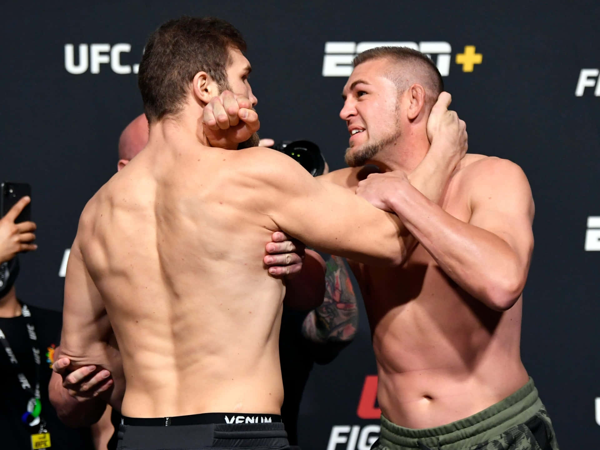兩名赤裸上身的MMA拳手在UFC賽事中鎖定纏鬥姿勢。