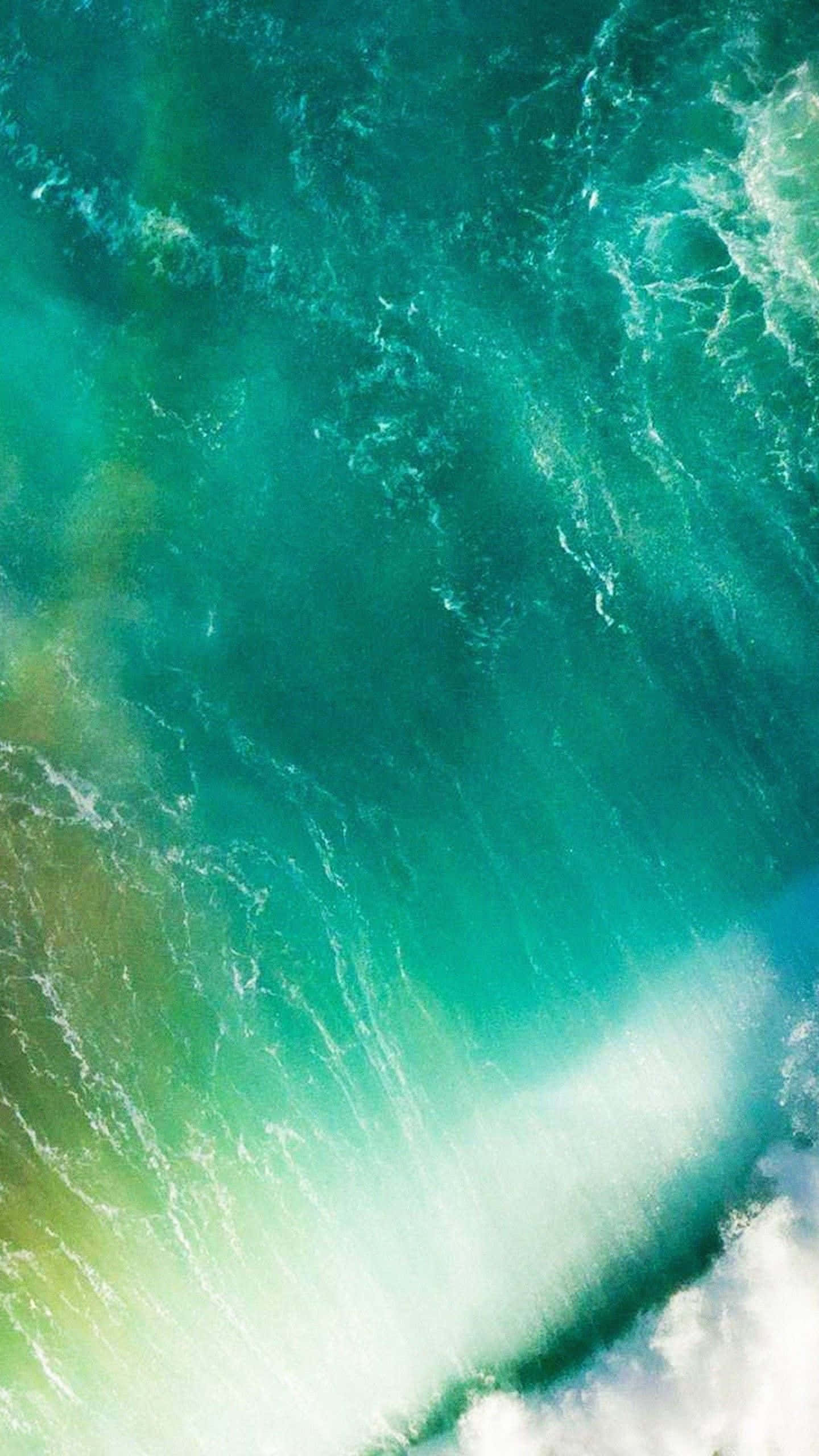 iOS 1 海浪頂視圖 壁紙 — 從高空俯瞰，藍綠色海浪拍打岩石海岸，激起白色泡沫。