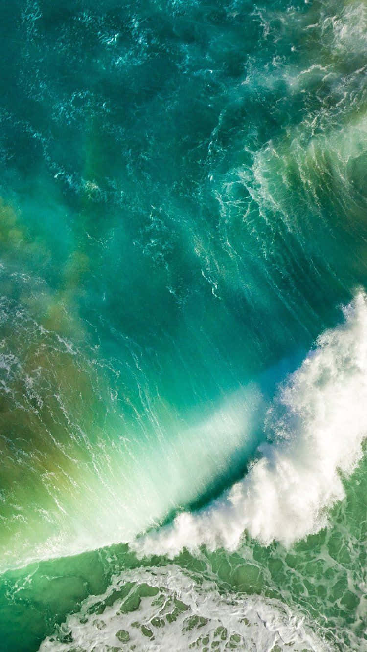iOS 1 綠色海浪拍岸 壁紙 — 從高空俯瞰，碧綠色的海浪翻騰，激起白色泡沫，動感十足。