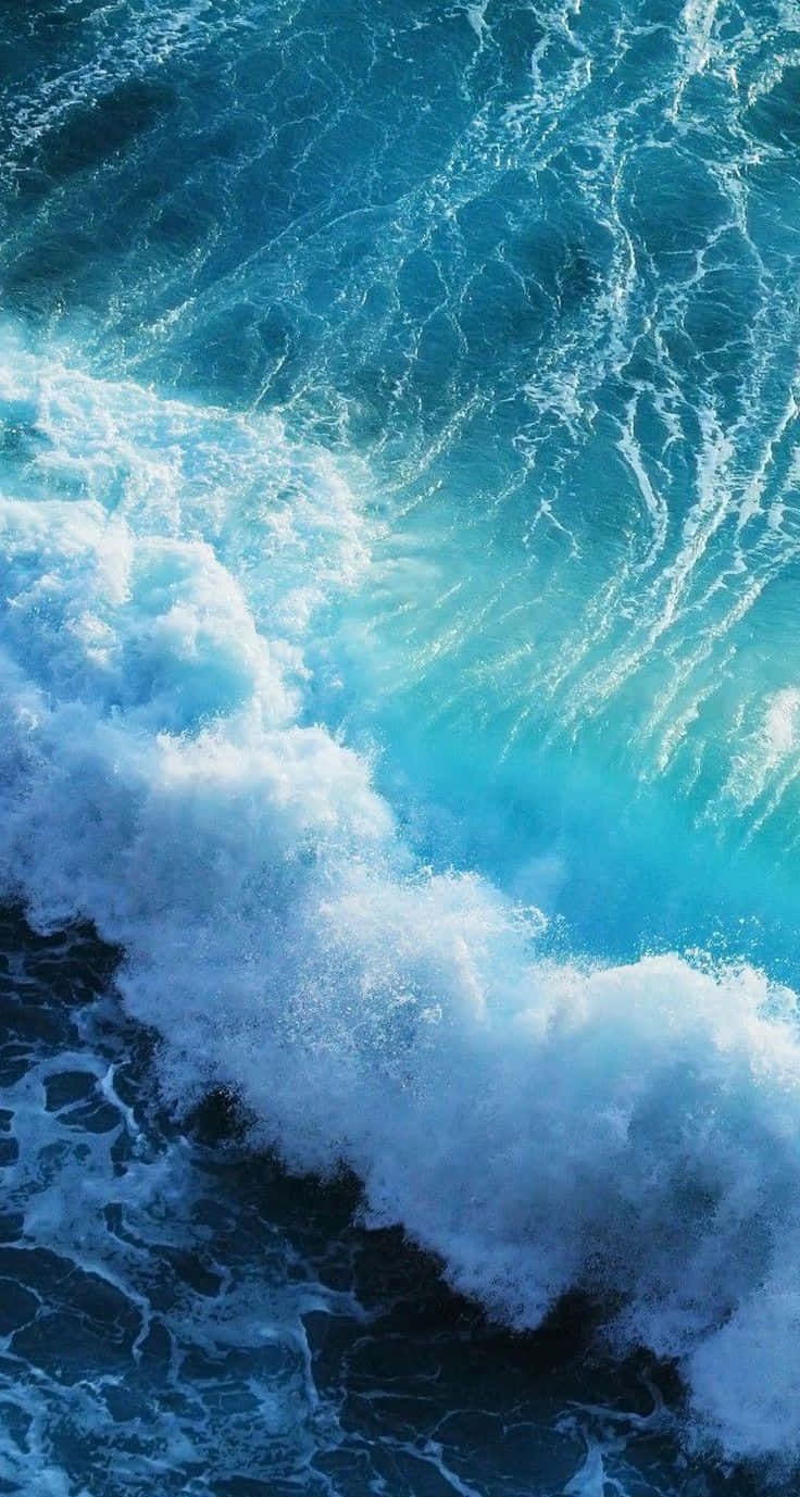 iOS 1 藍色衝擊海浪 壁紙 — 一道強勁的海浪拍打著深藍色的海水，激起白色泡沫，呈現動態的特寫鏡頭。