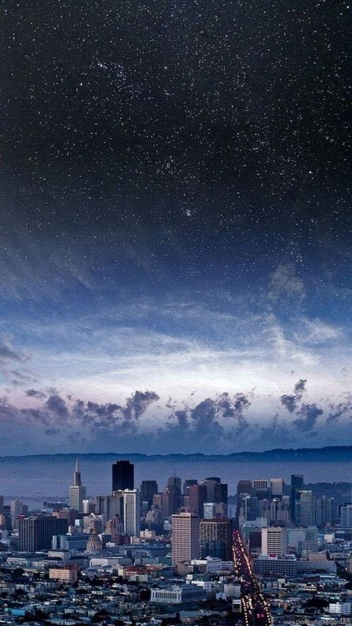 iOS 8 城市夜景 壁紙 — 城市天際線，星空下，發光路燈和縷縷雲彩。