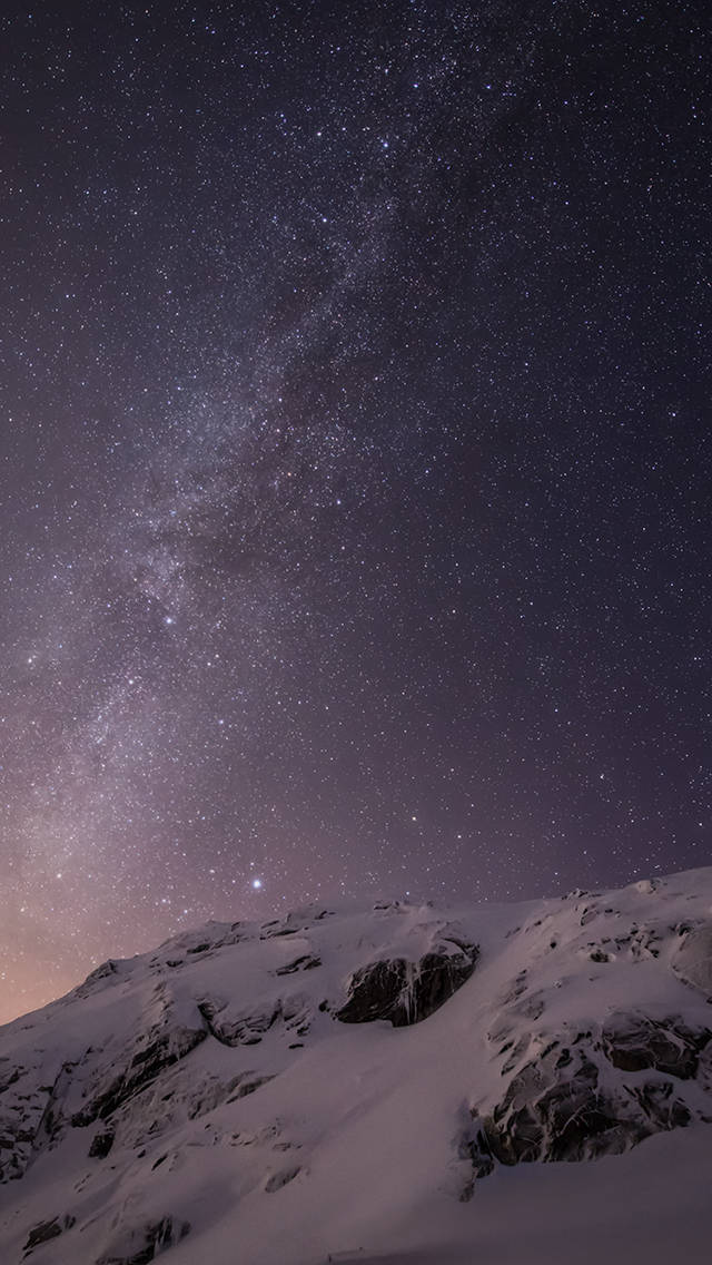 白雪覆蓋的山峰，在繁星點點的夜空下，銀河清晰可見。