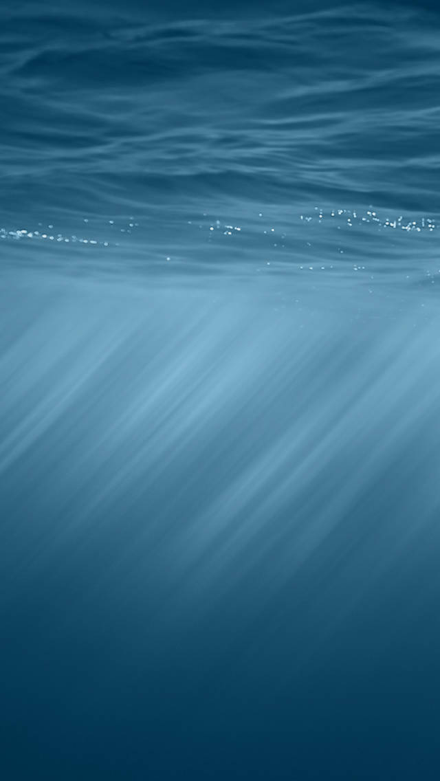 iOS 8 藍海寧靜 壁紙 — 陽光穿透海面，在水下投射出空靈的藍色光線。