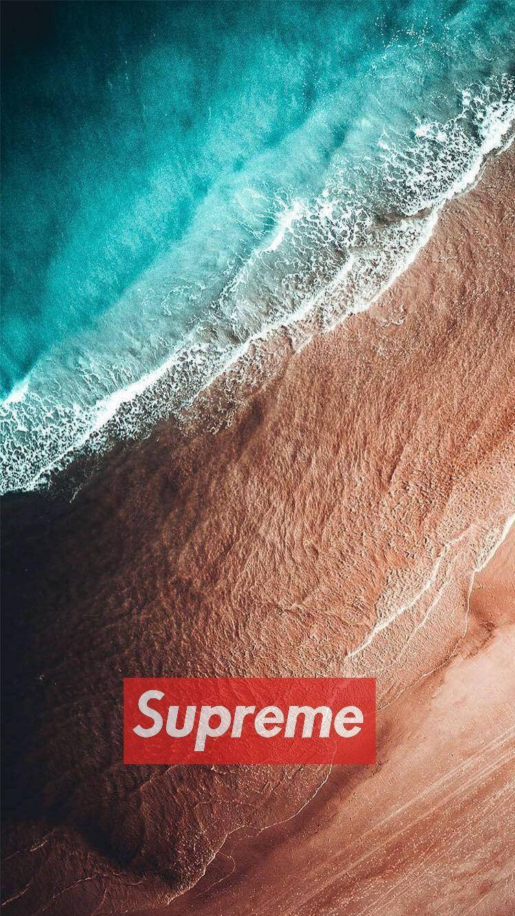 iOS Dope Supreme 海灘風 壁紙 — 從高空俯瞰，青綠色的海浪拍打著質感豐富的棕色沙灘，上面覆蓋著紅色的Supreme標誌。