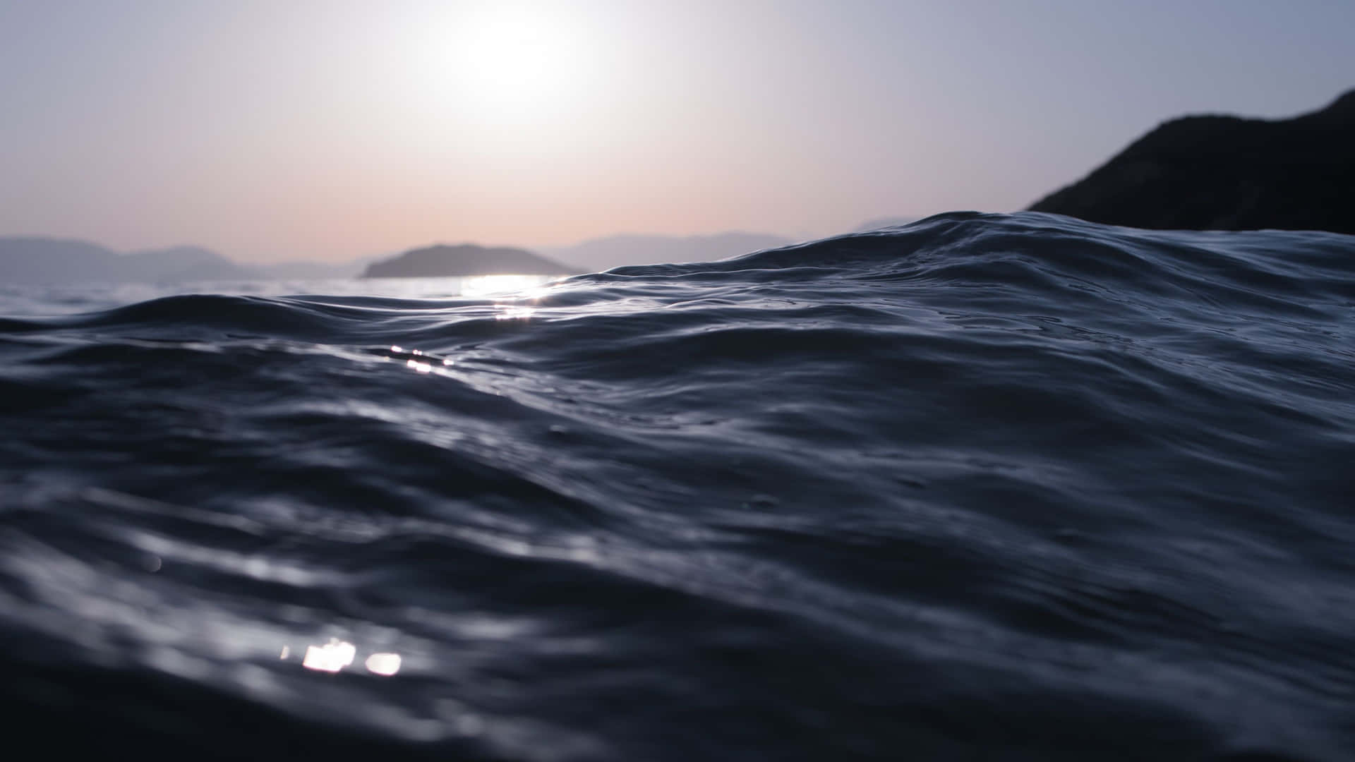 海浪在柔和暮色陽光下泛起漣漪，遠方島嶼隱約可見。