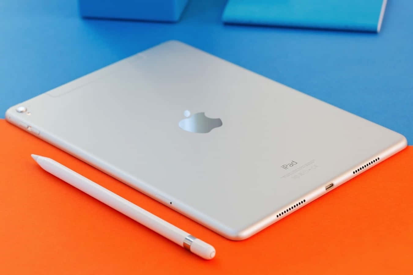 銀色 iPad 帶觸控筆放在橙色和藍色表面上