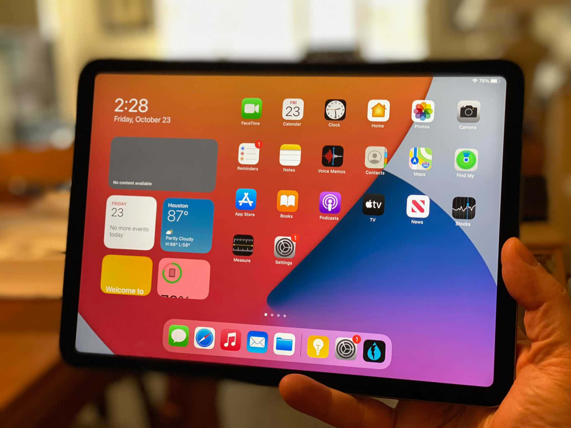 手拿著iPad，顯示帶有應用程式和天氣小工具的主屏幕。