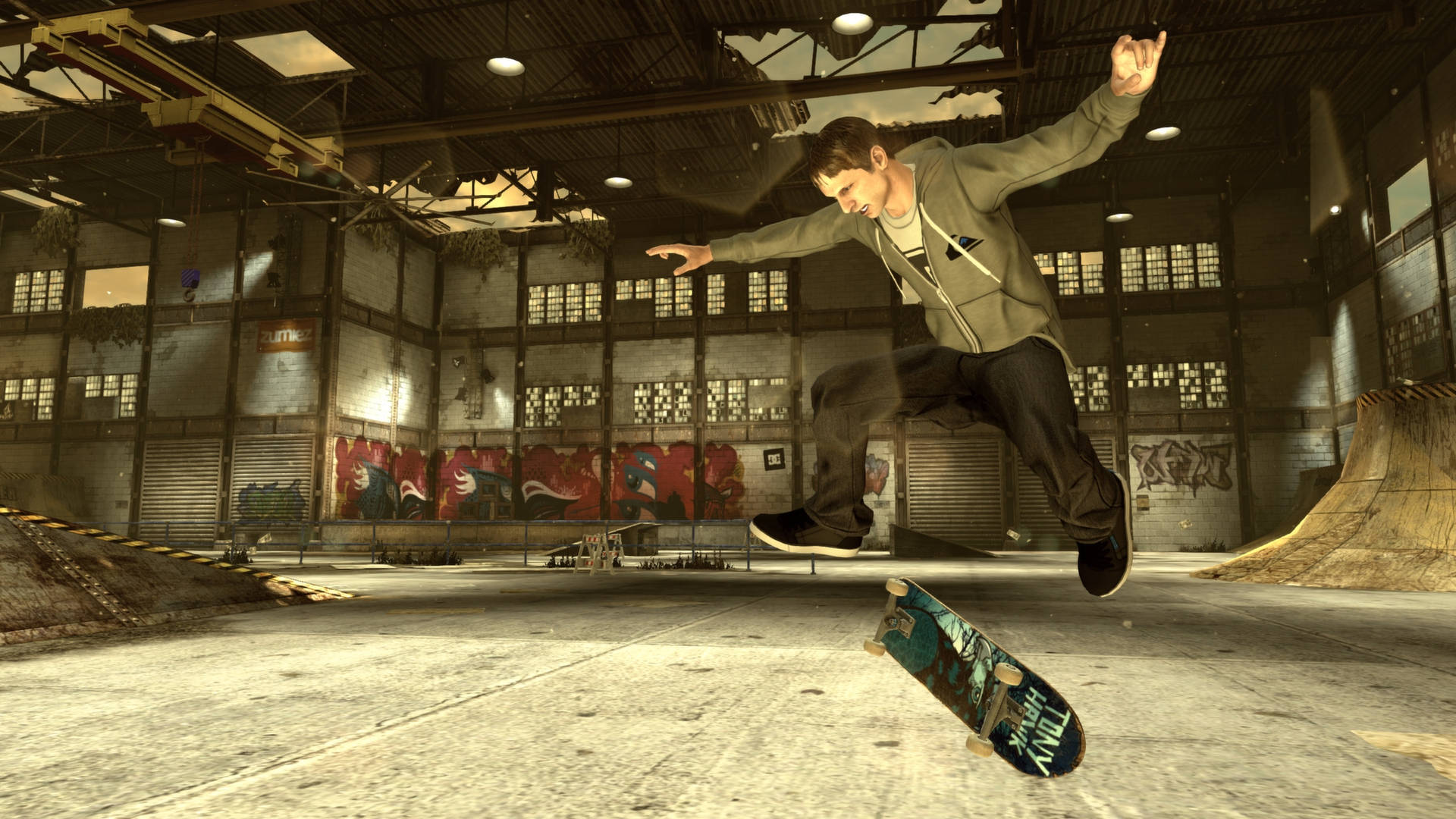 iPad Pro《Tony Hawk》於廢棄滑板場 壁紙 — 一名滑板手在半空中於一個佈滿塗鴉和坡道的工業倉庫內表演技巧。
