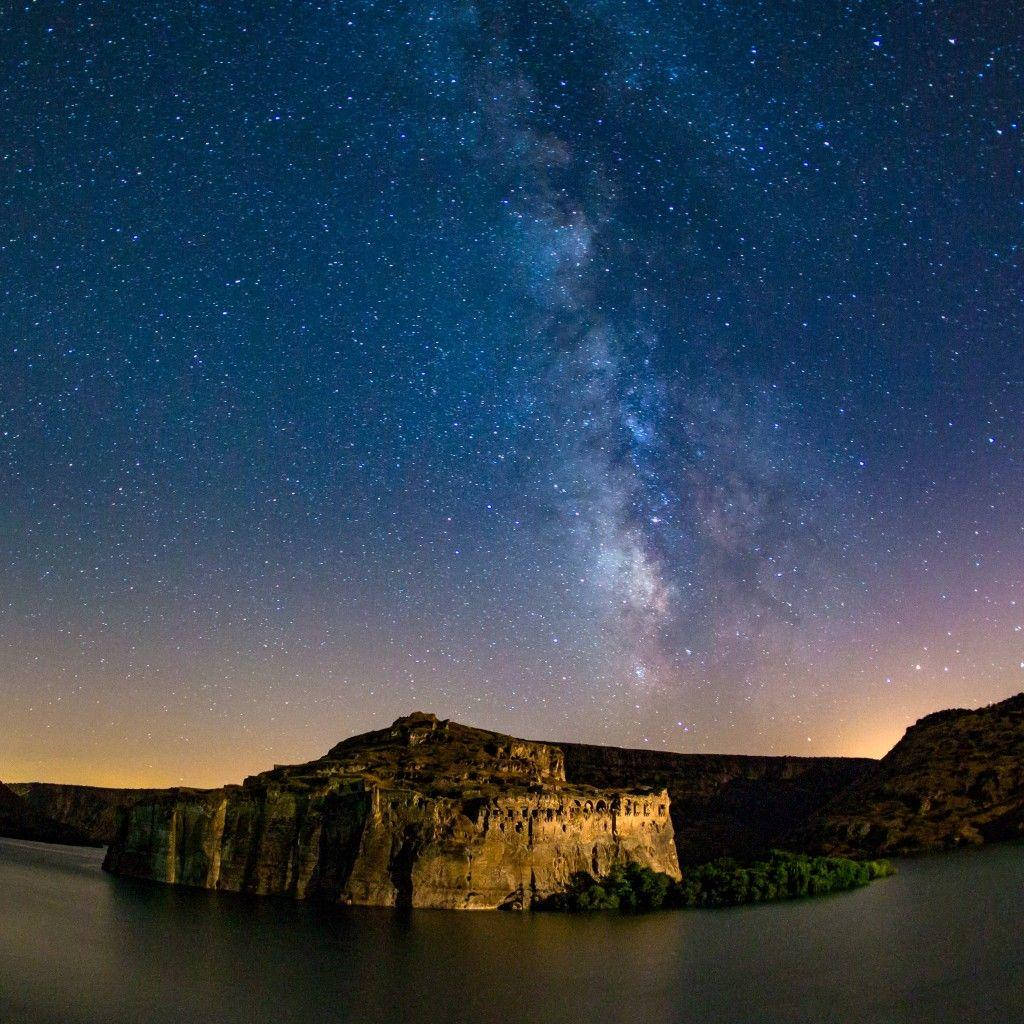 iPad Pro 星夜岩石島 壁紙 — 銀河系在星空下平靜的水面上拱起，倒映著古老的懸崖遺址。