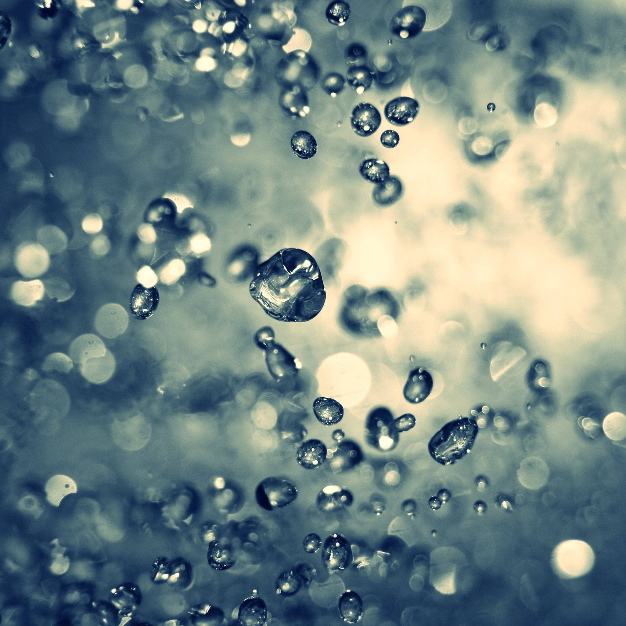 水滴iPad Retina顯示 壁紙 — 閃爍的水滴懸浮在夢幻般的藍色和奶油色散景背景中。