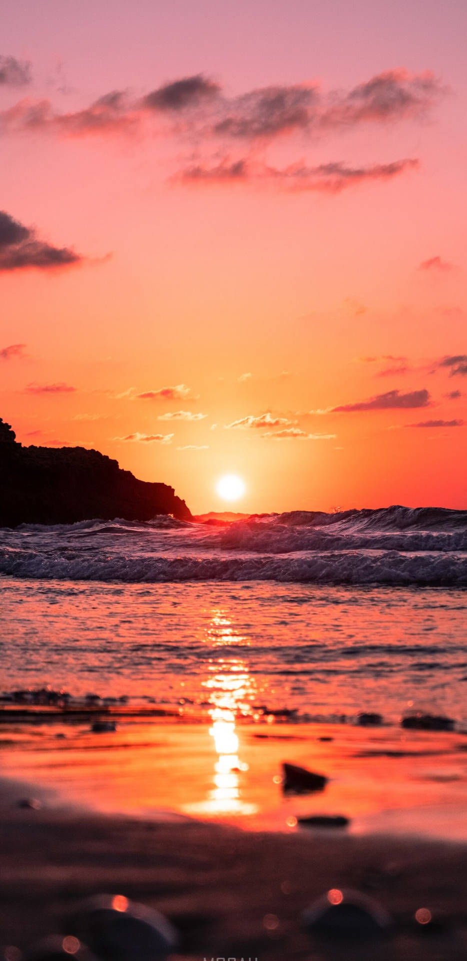 夕陽下的海洋，海浪拍打岩石海岸