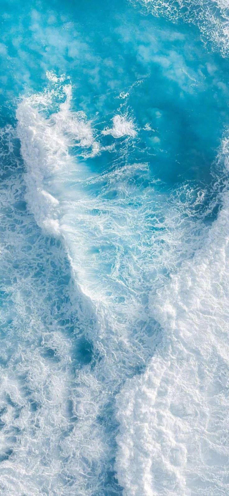 在明亮陽光下，綠松石色海洋波浪與白色泡沫撞擊。