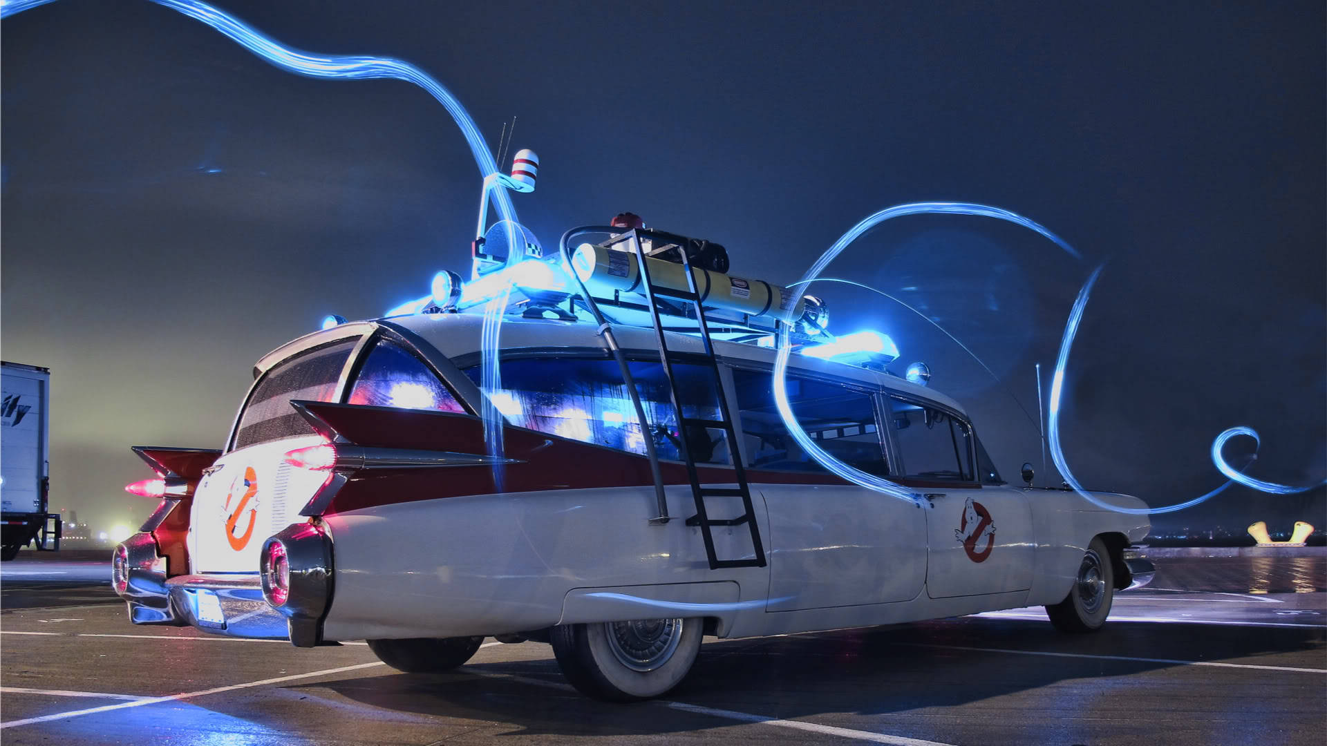 閃電夜景中的凱迪拉克（iPhone拍攝） 壁紙 — Ghostbusters Ecto 1 汽車在夜間黑暗的停車場中發出藍色光芒的軌跡。