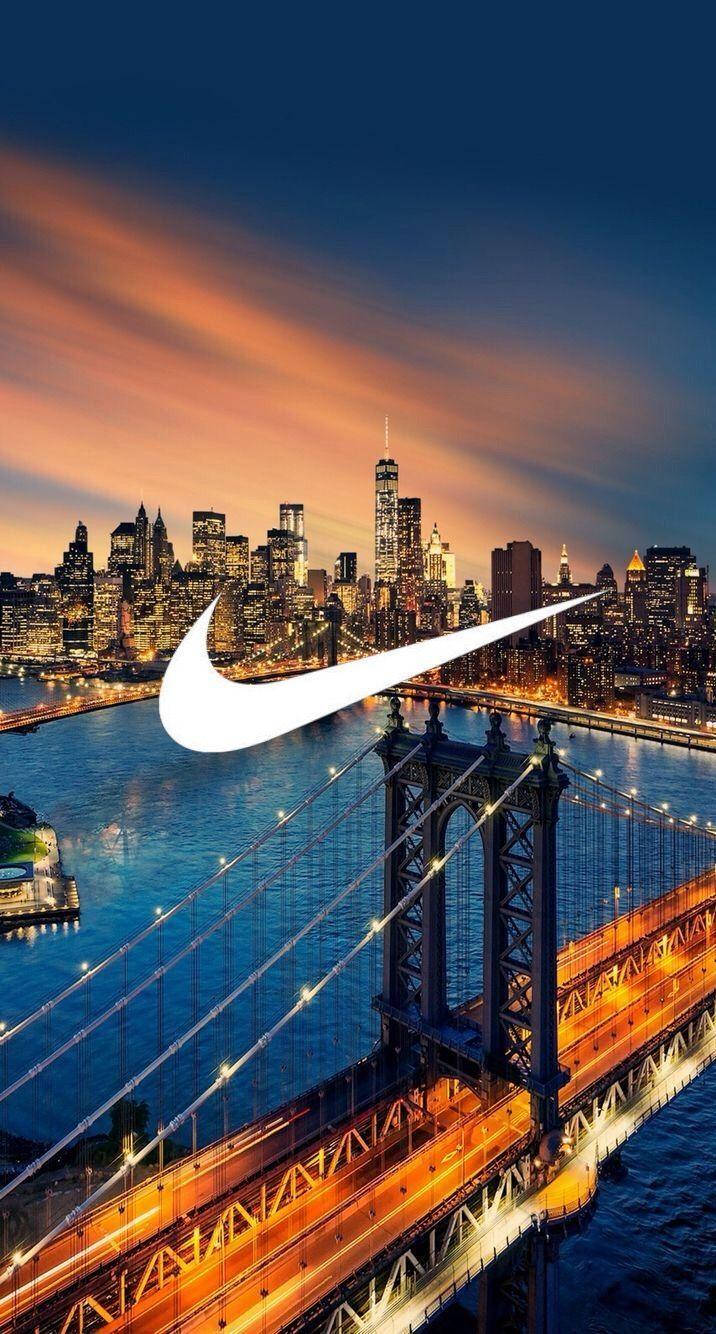 金門大橋耐克 iPhone 背景 壁紙 — 發光的Nike標誌疊加在布魯克林大橋和曼哈頓天際線上的鮮豔日落。