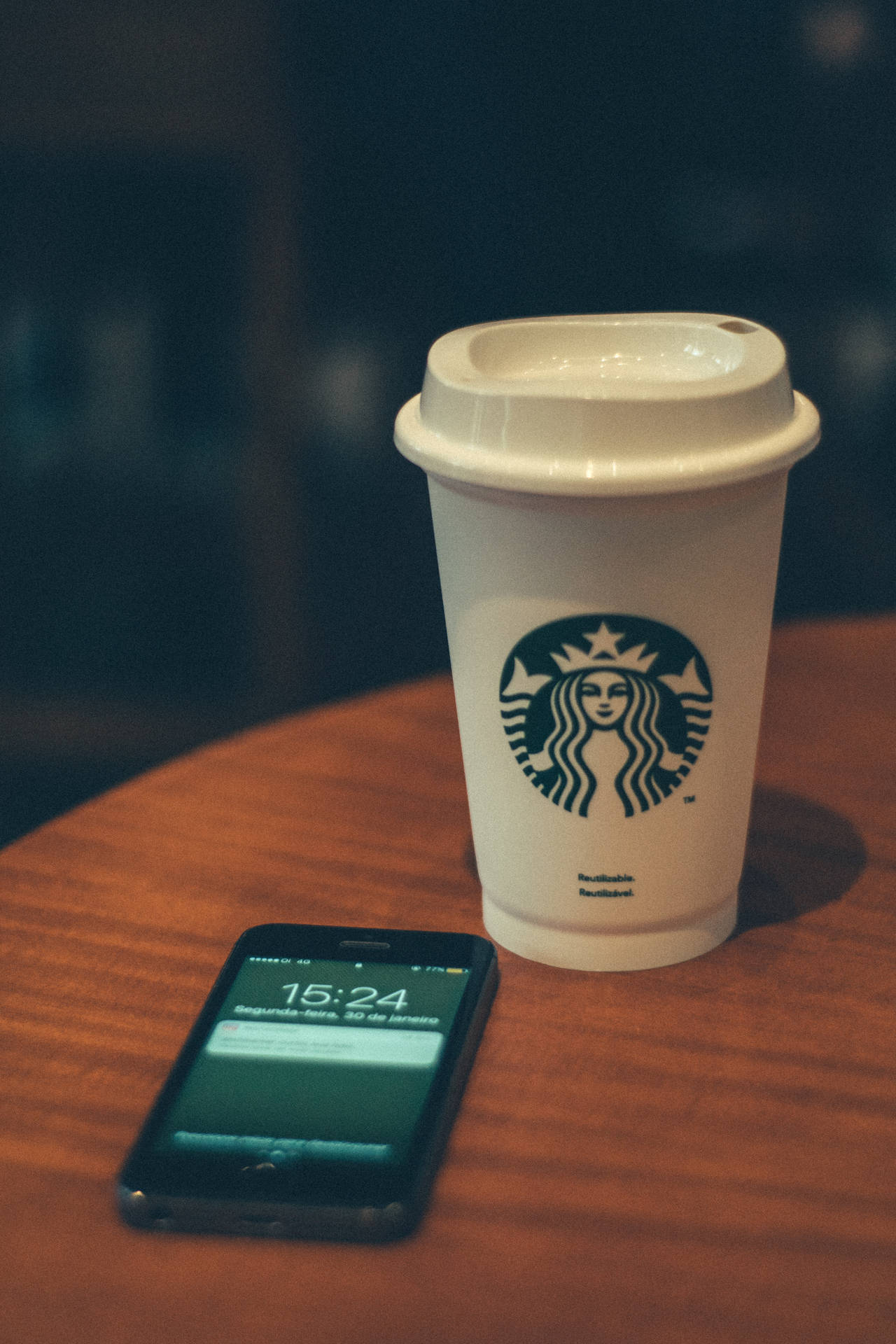 咖啡館木桌上的Starbucks咖啡杯和智能手機。 — 蘋果 壁紙