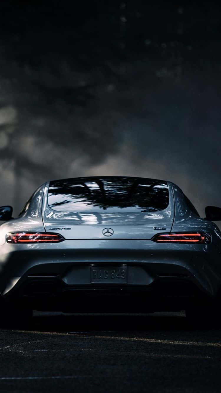 經典梅賽德斯車與iPhone顯示畫面 壁紙 — 從後方觀看的時尚銀色 Mercedes-AMG 跑車，紅色尾燈在黑暗煙霧背景下發光。