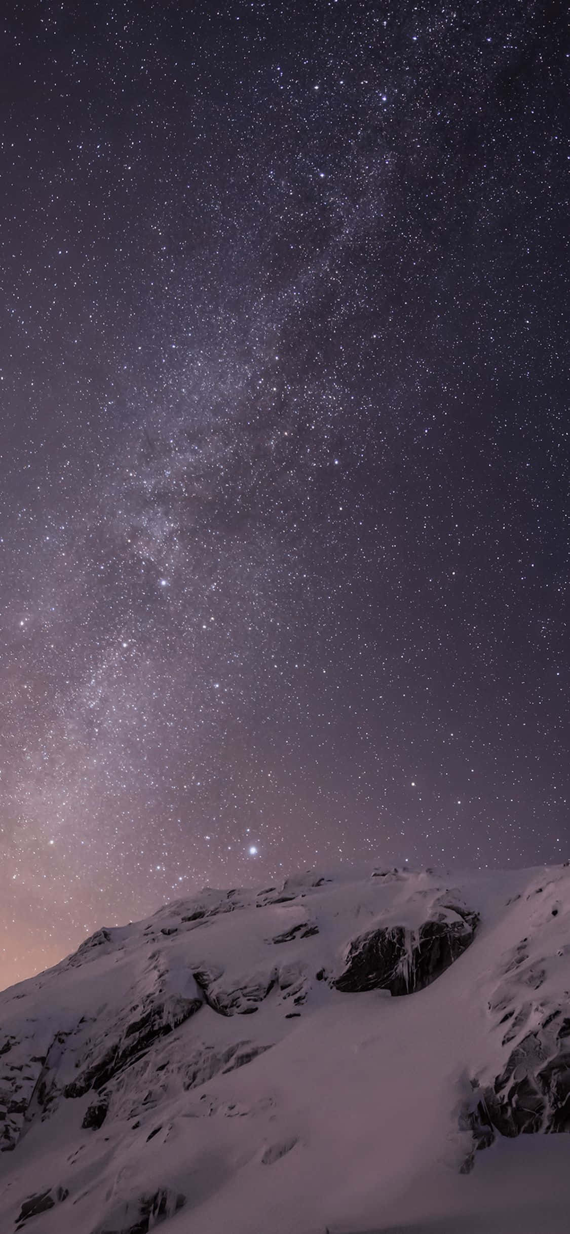 iPhone 5s 原廠壁紙：雪山夜空 壁紙 — 白雪覆蓋的山峰在令人嘆為觀止的星空下升起，銀河在頭頂閃耀。