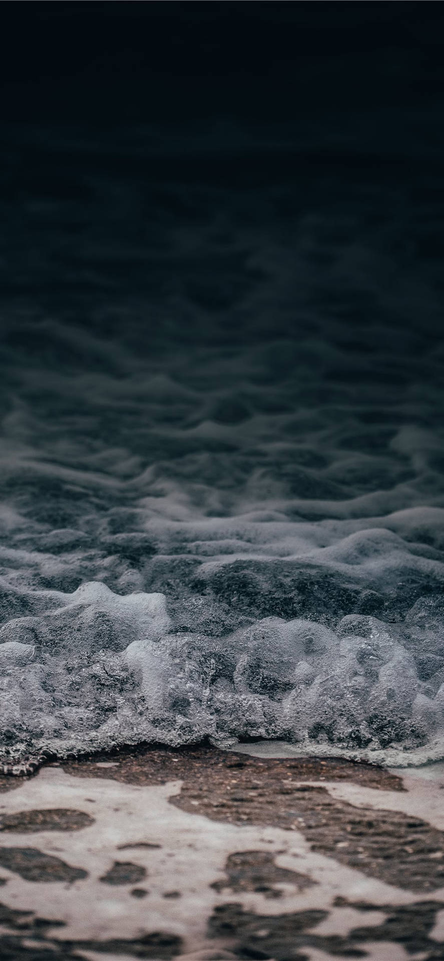 泡沫海浪在暮色中滾向黑暗沙灘。
