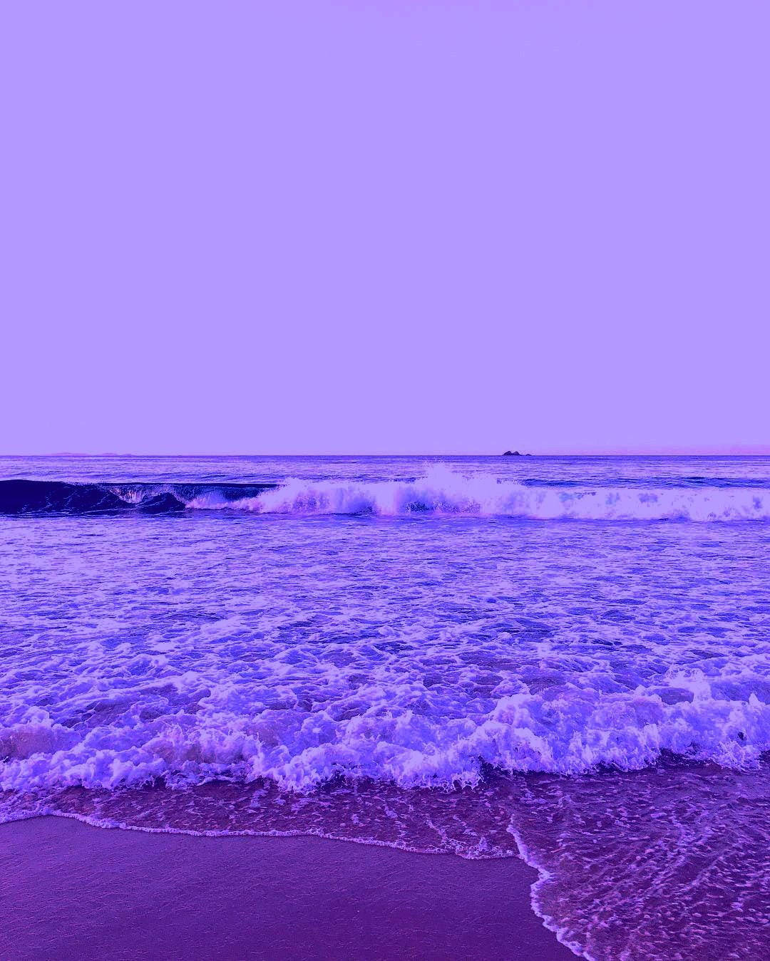 紫色的海浪在紫羅蘭色的天空下翻滾到沙灘上。