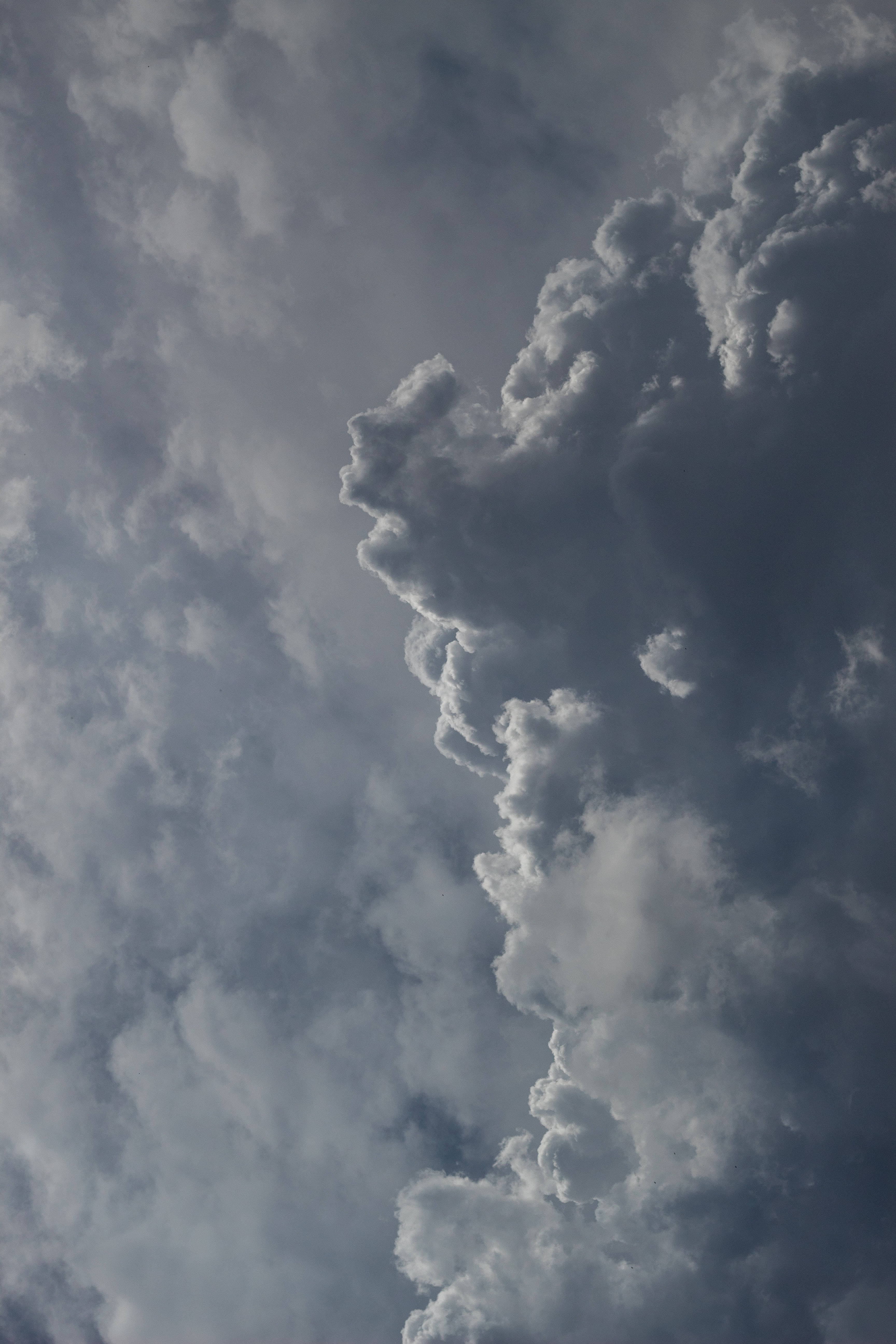 灰雲iPhone壁紙 壁紙 — 戲劇性的風暴雲在深灰和白色中旋轉，映襯著陰沉天空。