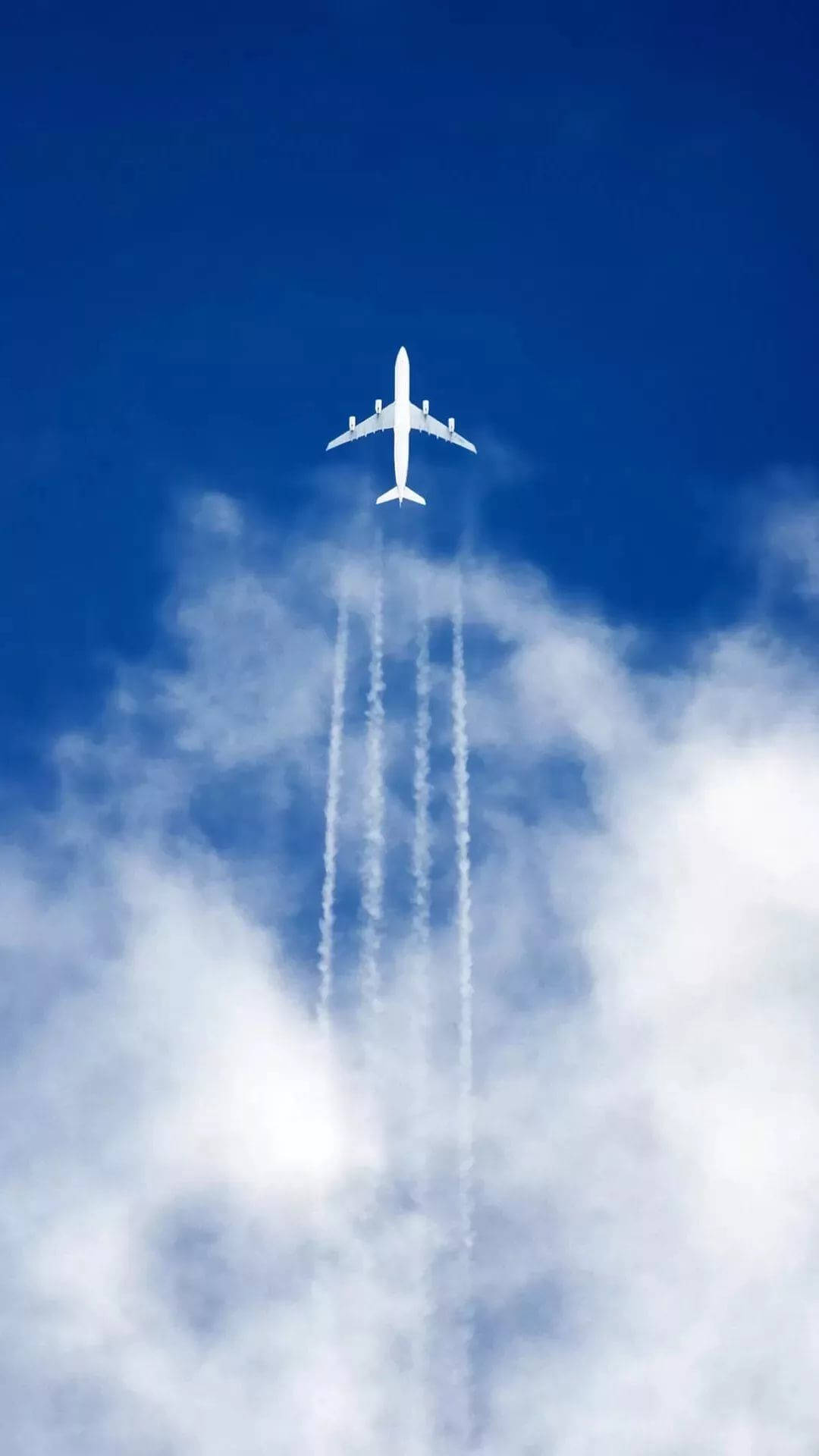 飛機空中俯拍 iPhone 壁紙 — 一架白色客機在鮮豔的藍天中翱翔，飛過蓬鬆的白雲，留下三條明顯的凝結尾跡。