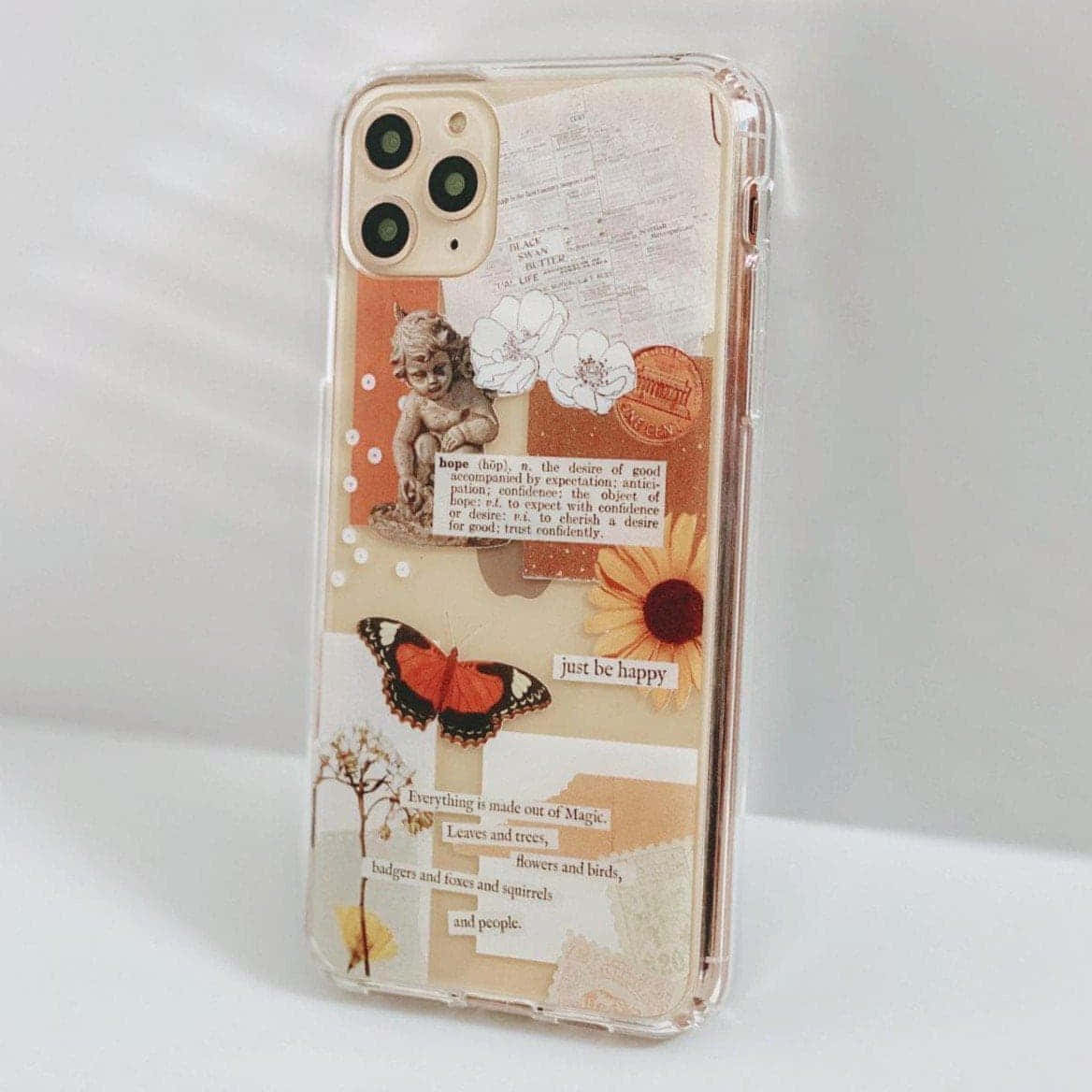 展現 iPhone 的優雅與美學設計 壁紙 — 透明手機殼，裝飾有復古拼貼元素，包括小天使、蝴蝶、向日葵和勵志語錄。
