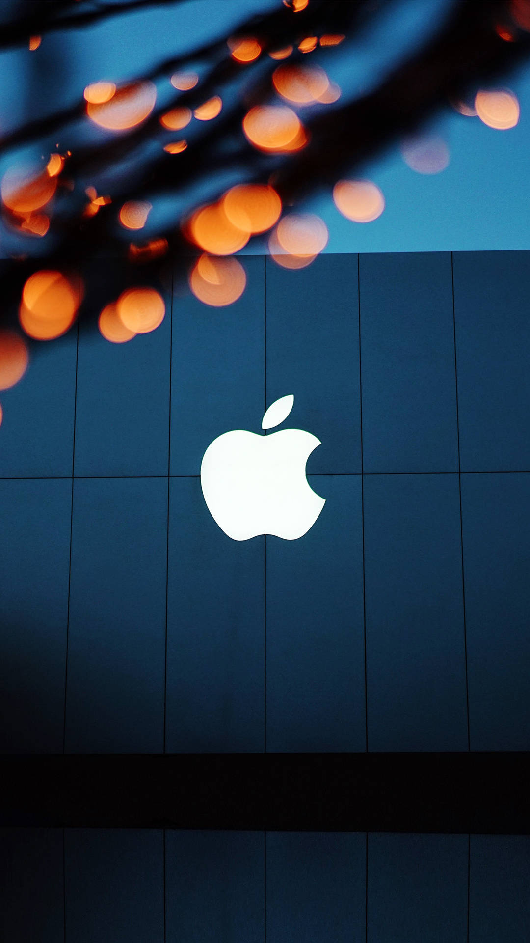 Apple標誌在藍色瓷磚牆上發光，背景有橙色燈光。