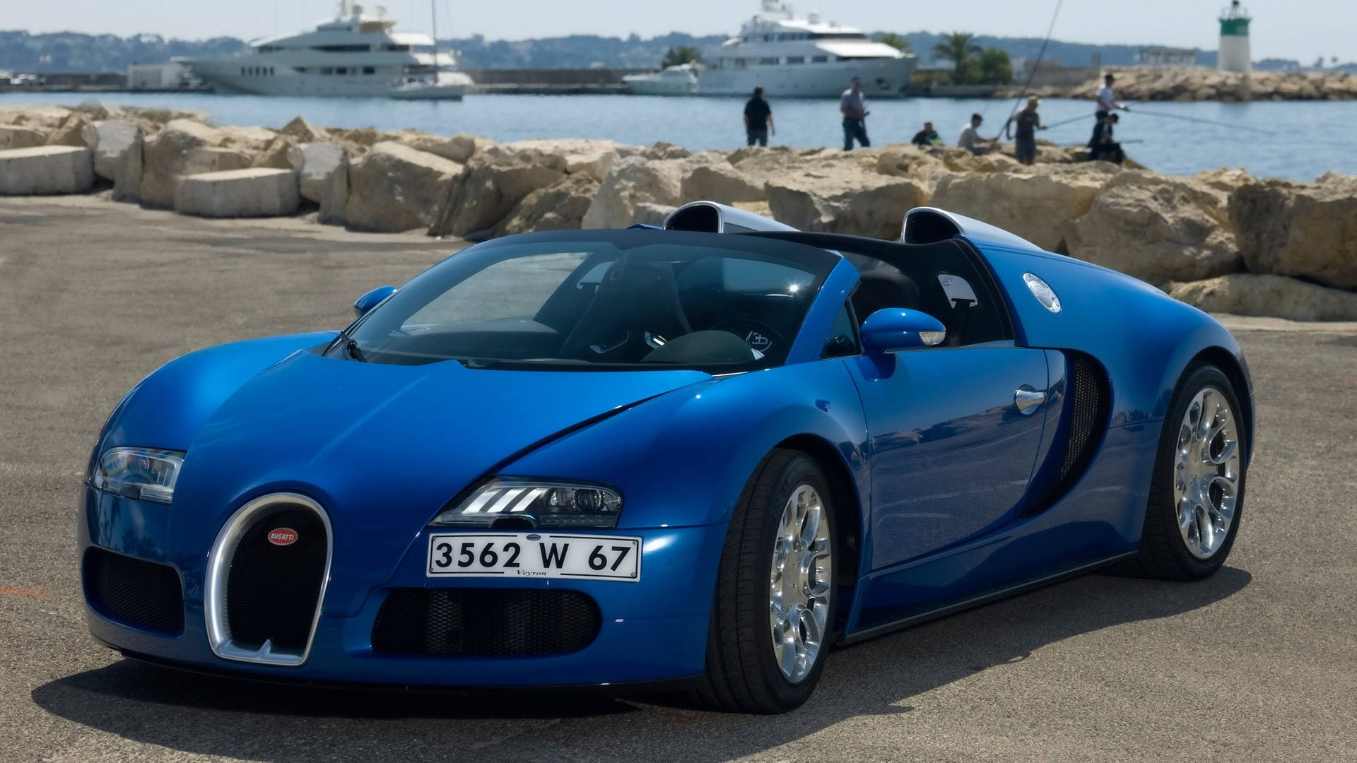 藍色布加迪海灘 iPhone 壁紙 — 一架閃亮的藍色Bugatti Veyron超級跑車停泊在陽光明媚的港口碼頭，背景有遊艇和人。