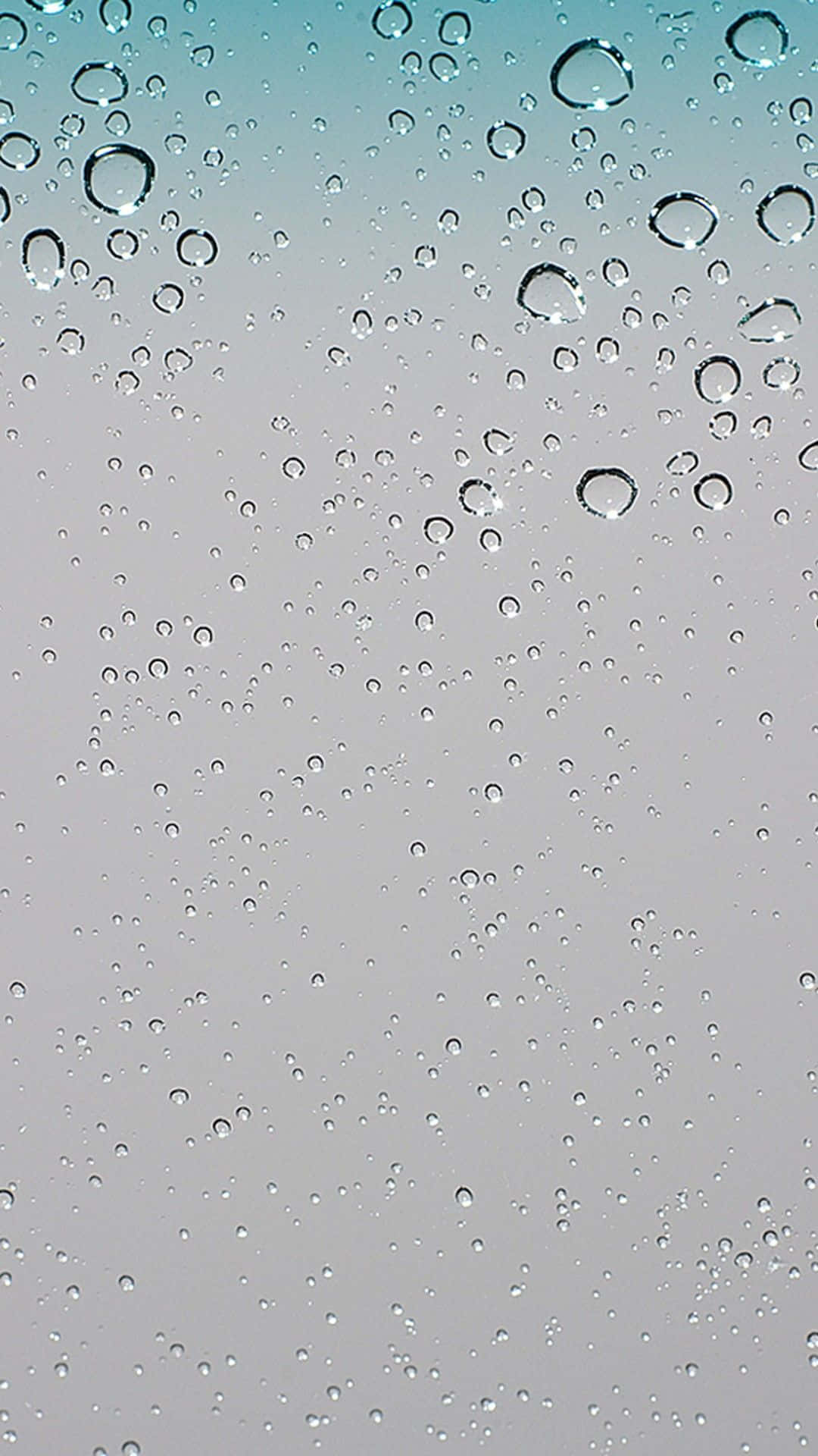 玻璃上雨滴的特寫，天空從青綠色到灰色的漸變。