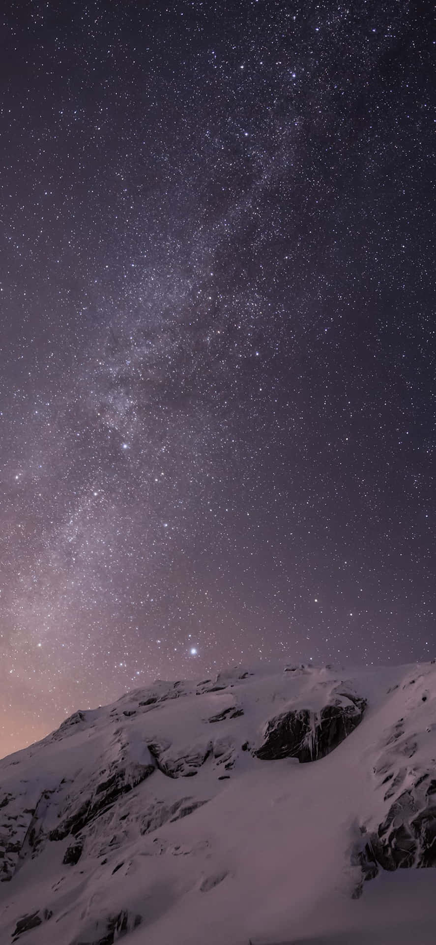 積雪的山脈在繁星點點的夜空下，銀河清晰可見。