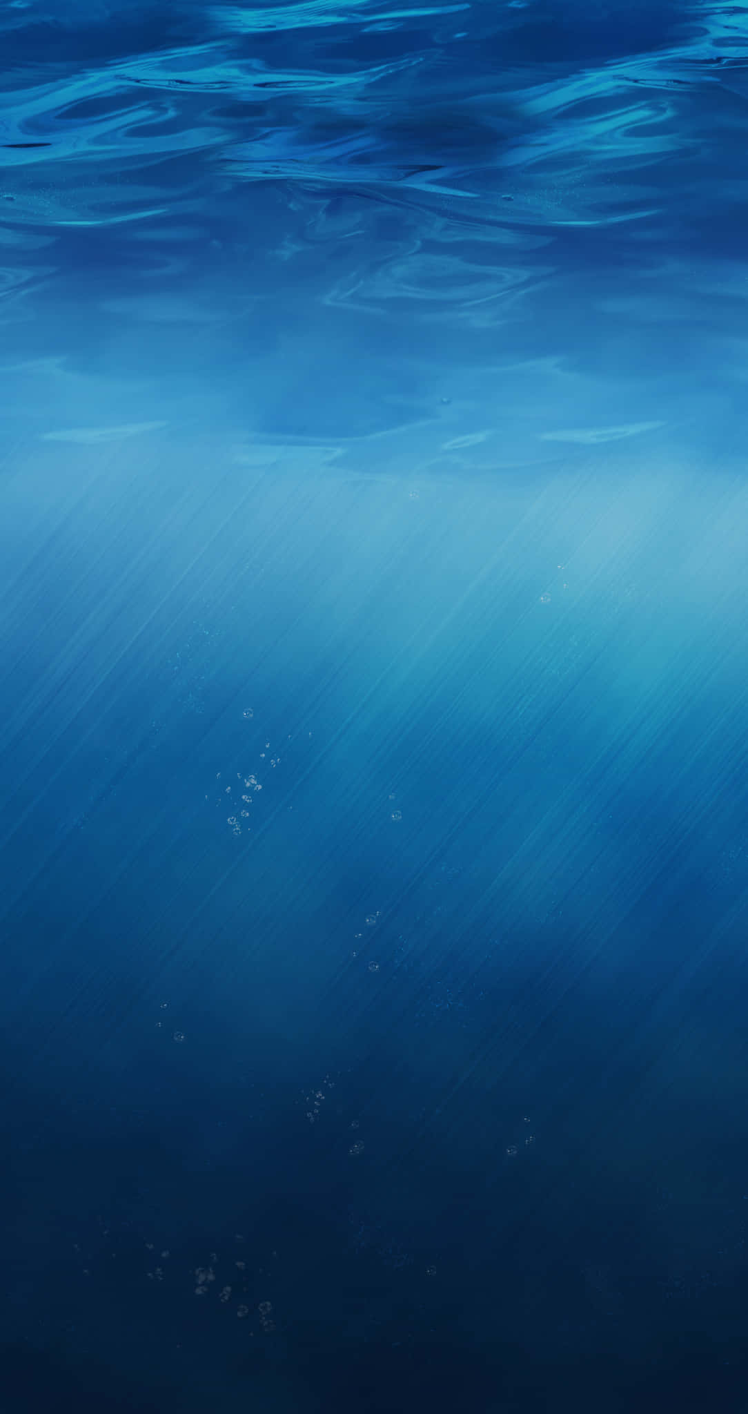 水下 iPhone 的深邃水域 壁紙 — 陽光穿透海面，在深藍色海水中投射出空靈的光線，並有浮動的氣泡。