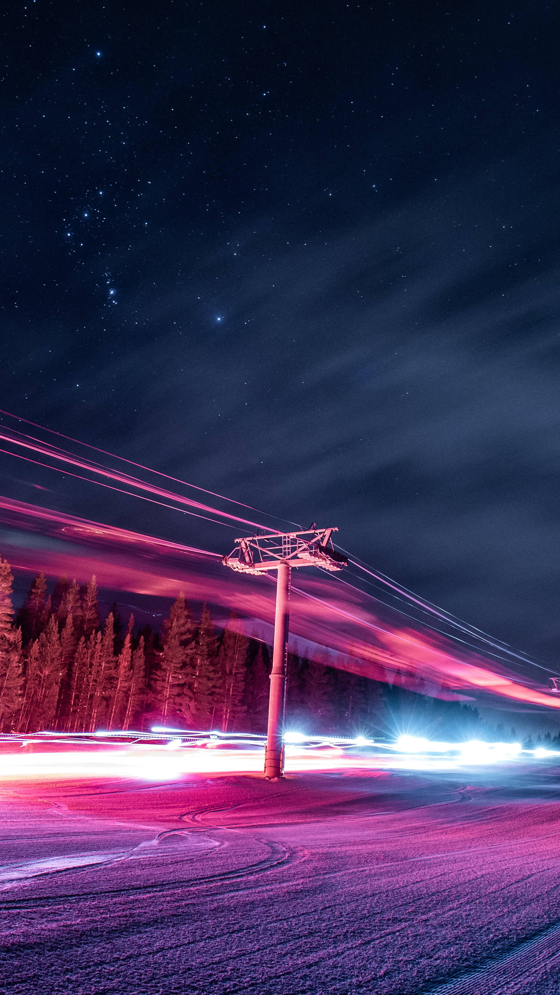 路邊霓虹美學 iPhone 壁紙 — 一條滑雪吊車柱矗立在繁星點點的夜空下，鮮豔的粉紅色和藍色光軌劃過白雪覆蓋的山景。
