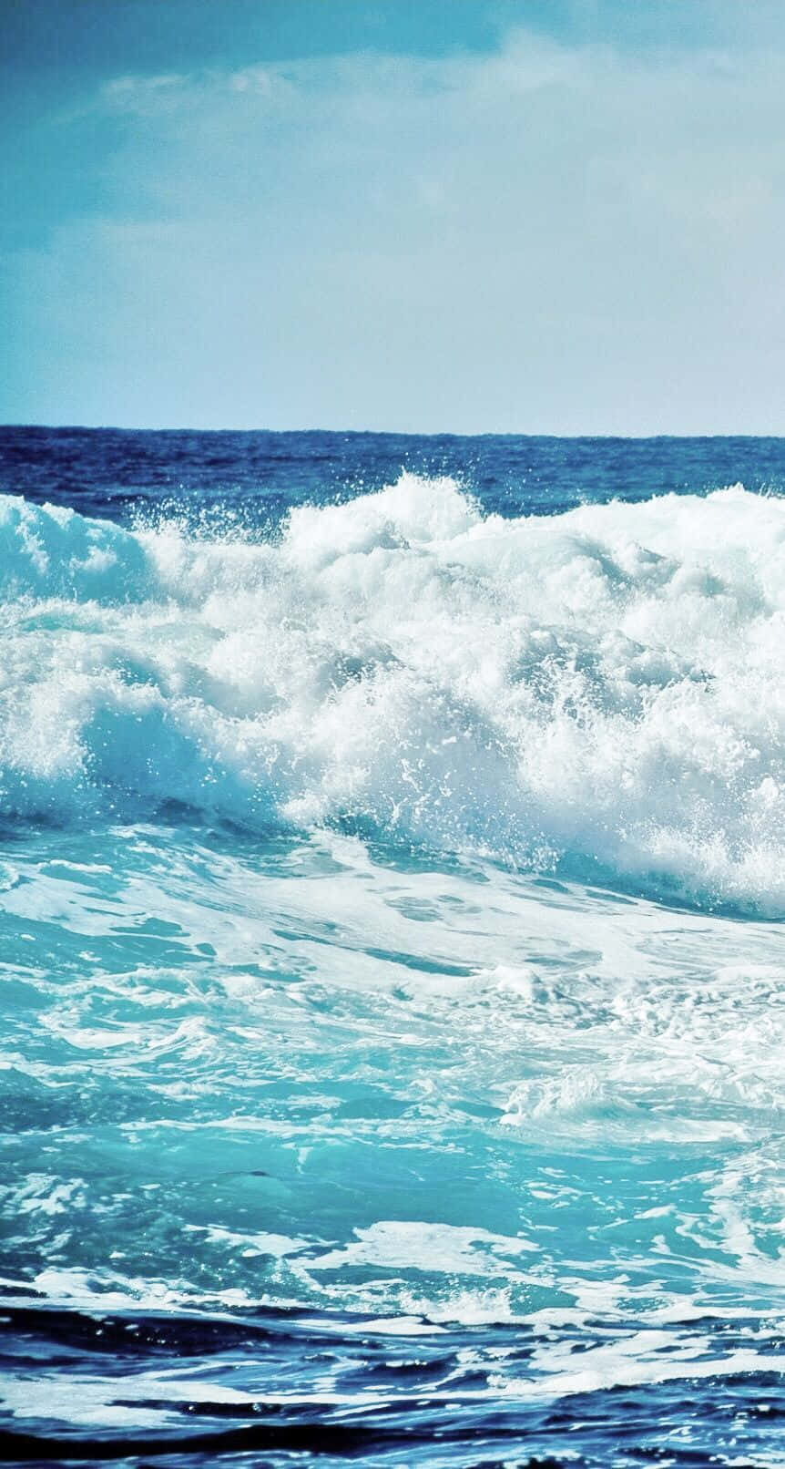 日間海浪 iPhone 壁紙 — 在清澈的藍天下，強勁的藍綠色海浪拍打著白色泡沫。