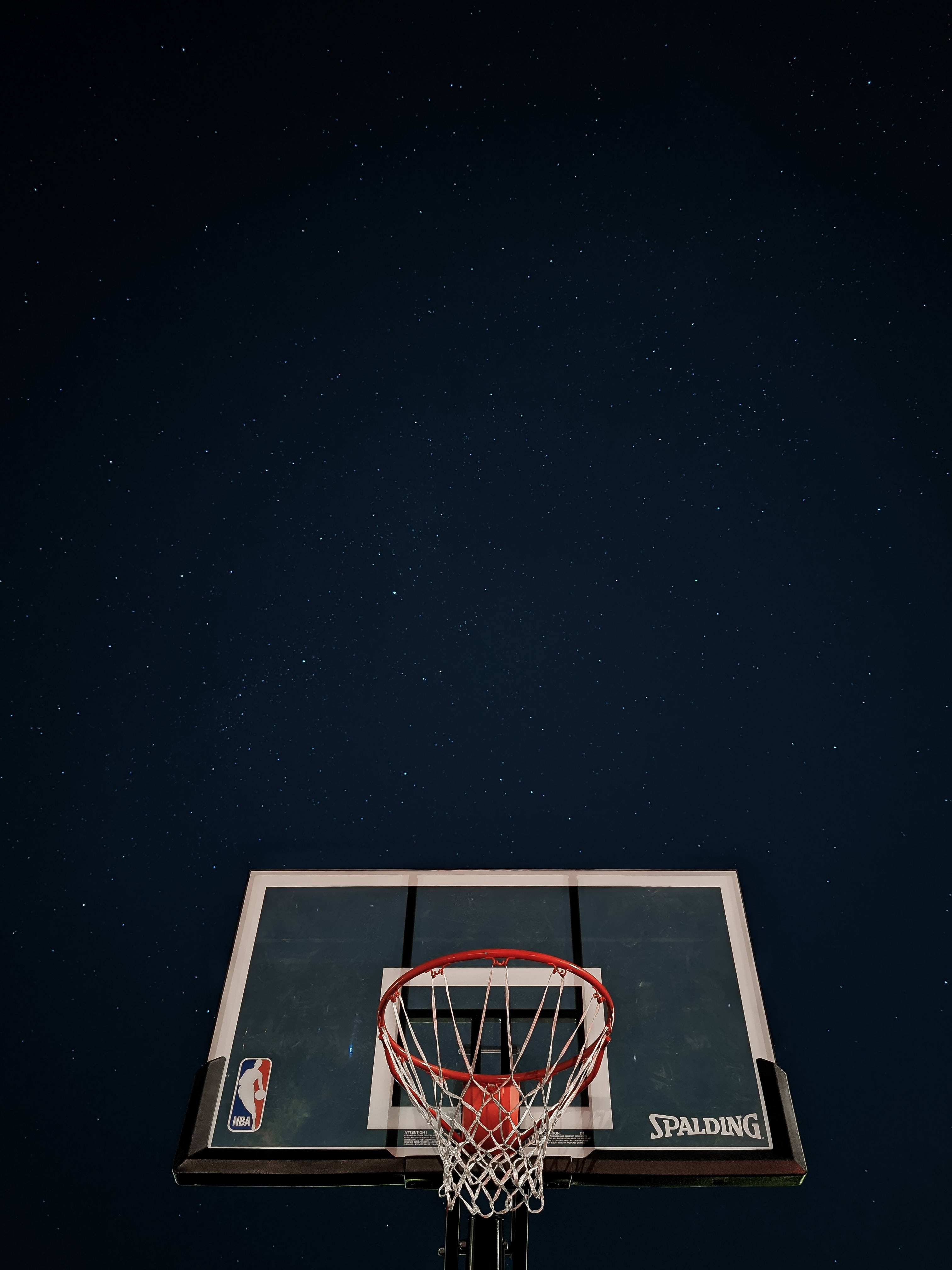 最酷的iPhone籃球戒指 壁紙 — 一個籃球框在星空下，帶有 Spalding 籃板和 NBA 標誌。
